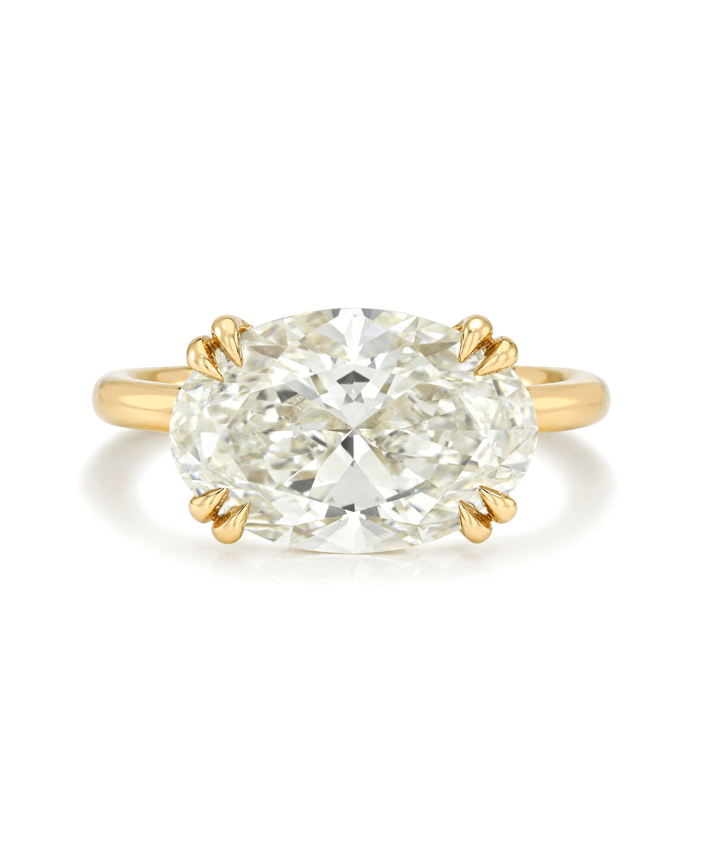 An oval brilliant cut diamond ring with a yellow gold band and double prong setting, photographed on a clean white background.