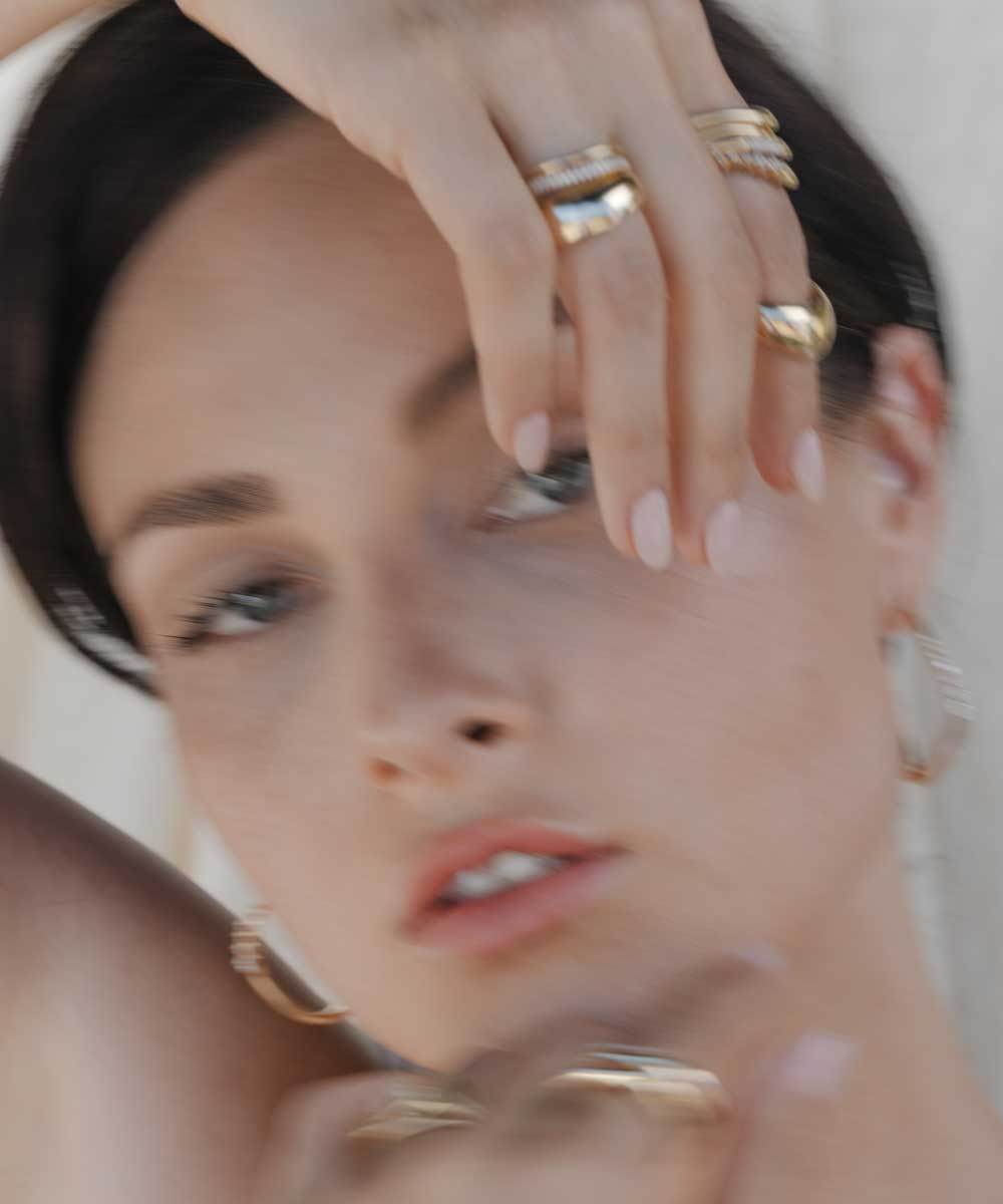 Unique engagement ring with gold-toned band and stones, close-up of stacked rings on a hand
