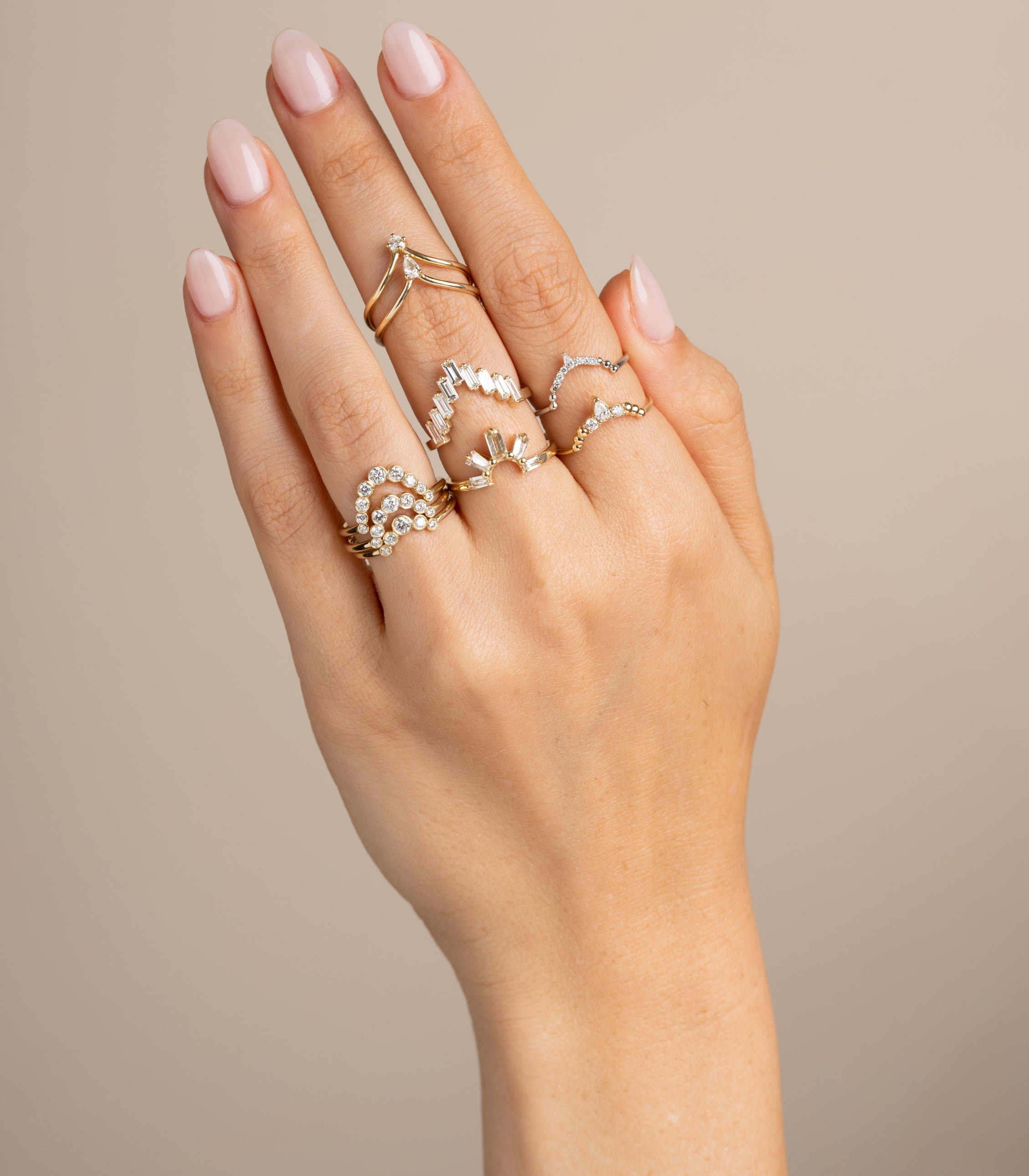 Unique engagement ring and stack of gold diamond rings on a hand, understated and asymmetrical