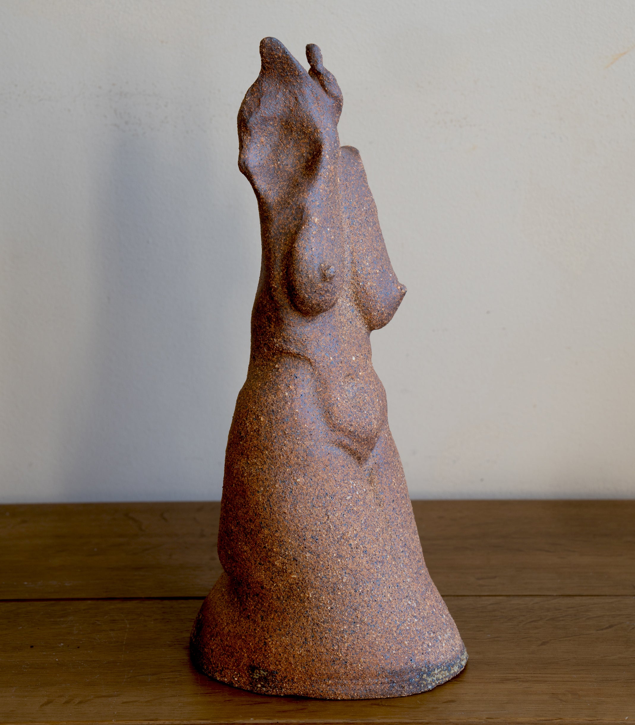 Standing Sculpture II by RM-001 rusted stone-like standing figure sculpture with textured finish in soft light