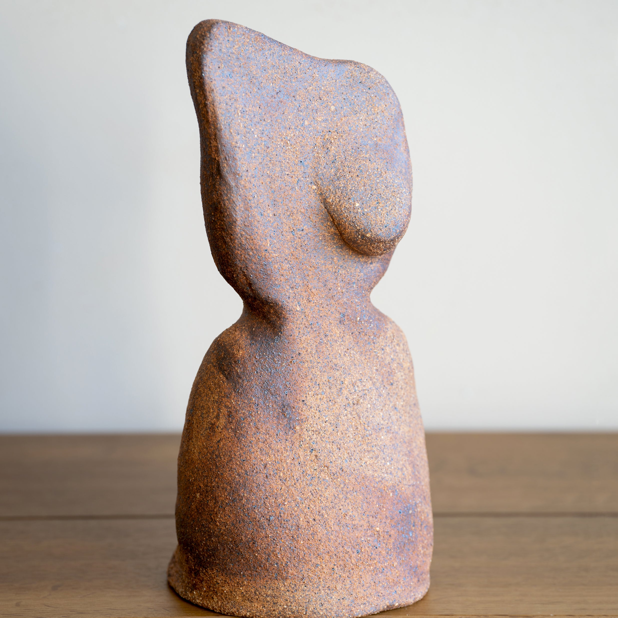 Minimal RM-003 speckled rust and blue ceramic sculpture with abstract head silhouette on a wood floor