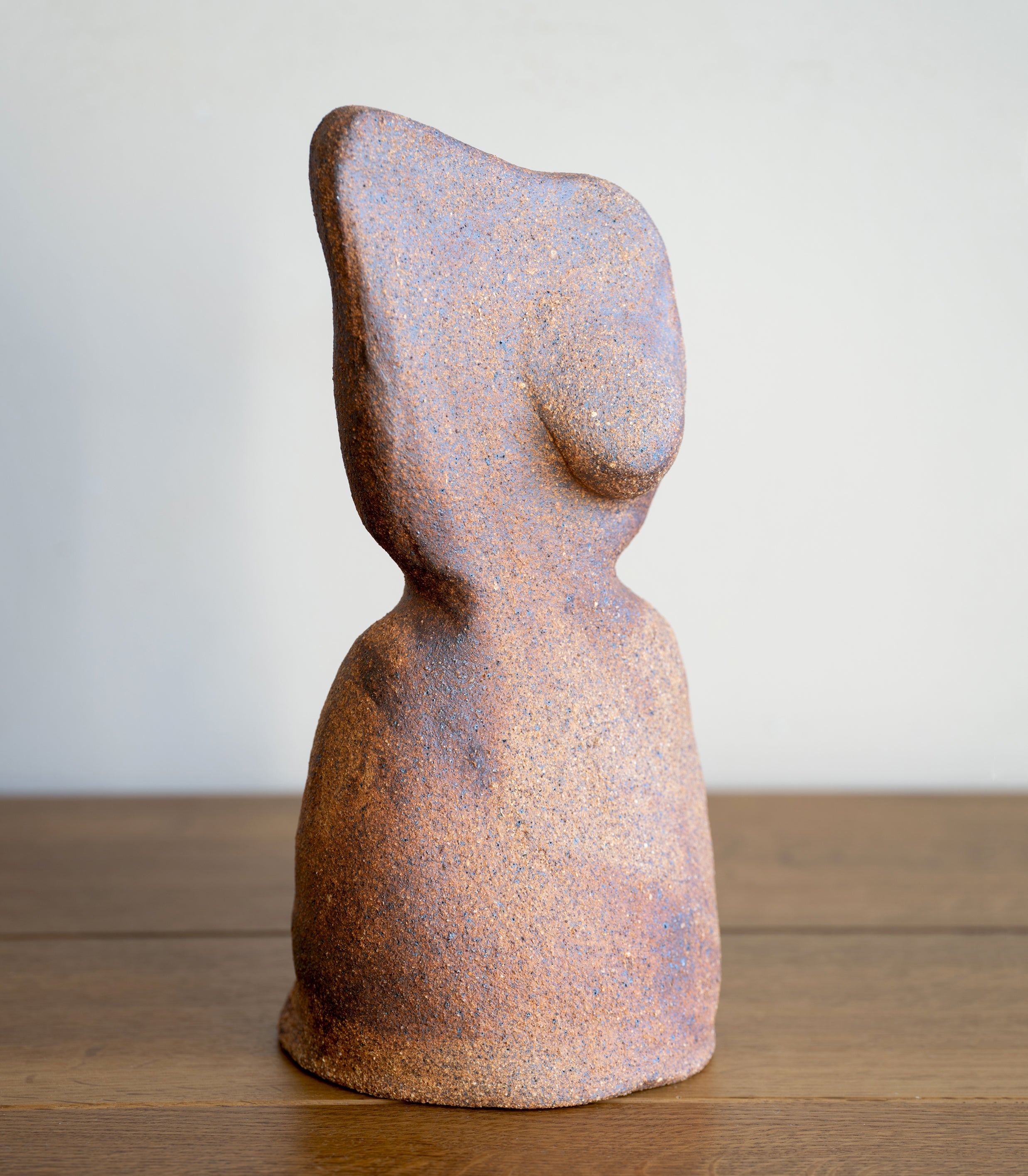 Minimal RM-003 speckled rust and blue ceramic sculpture with abstract head silhouette on a wood floor