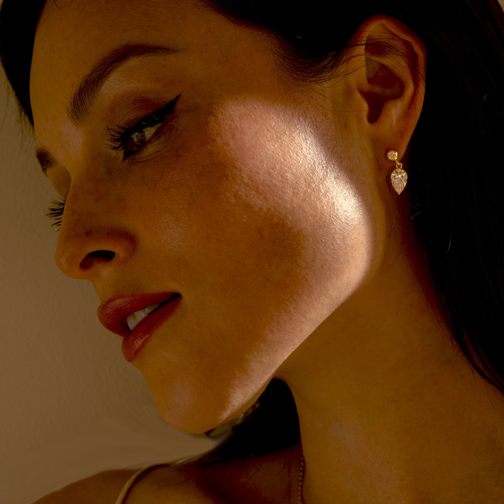 Gigi Earrings SK-E117-LGD-PBD-1.27 gold drop earrings with sparkling teardrop stones in warm light