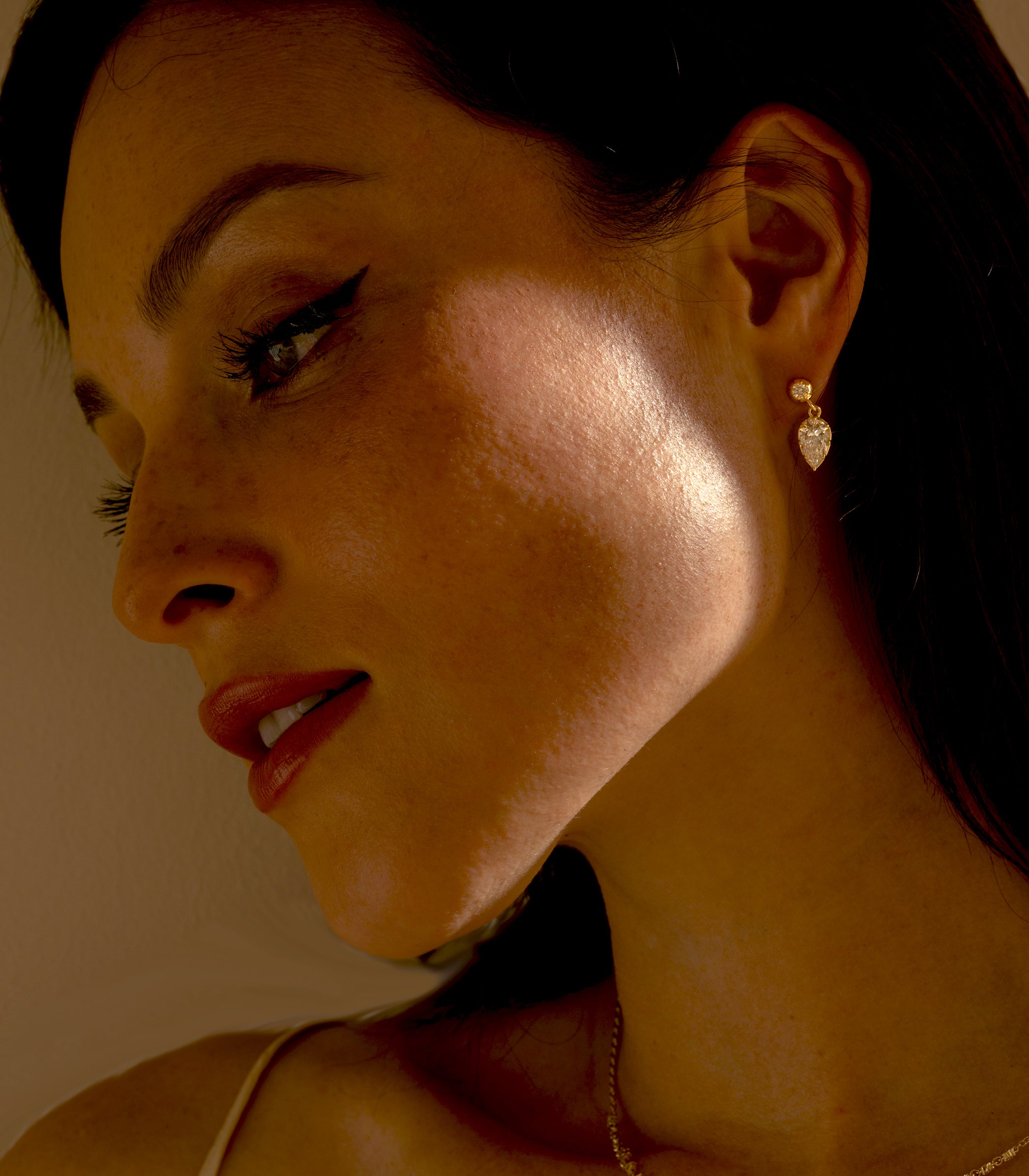 Gigi Earrings SK-E117-LGD-PBD-1.27 gold drop earrings with sparkling teardrop stones in warm light