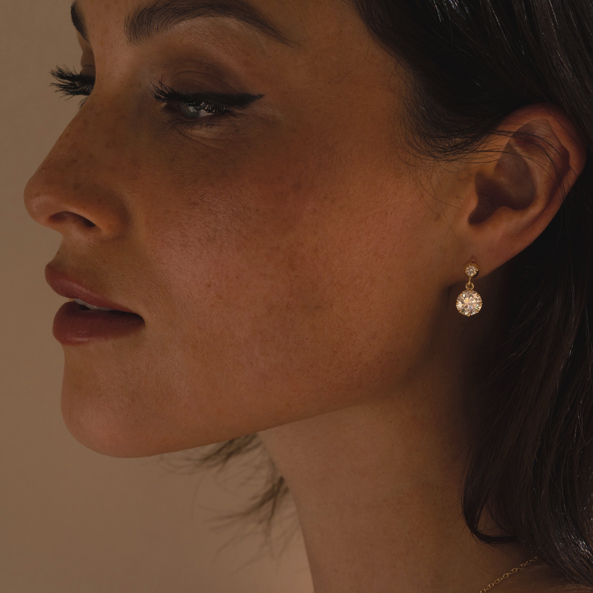 Gigi Earrings by SK-E117-ND-OEC-4.02: gold drop earrings with round sparkling stones, close-up portrait
