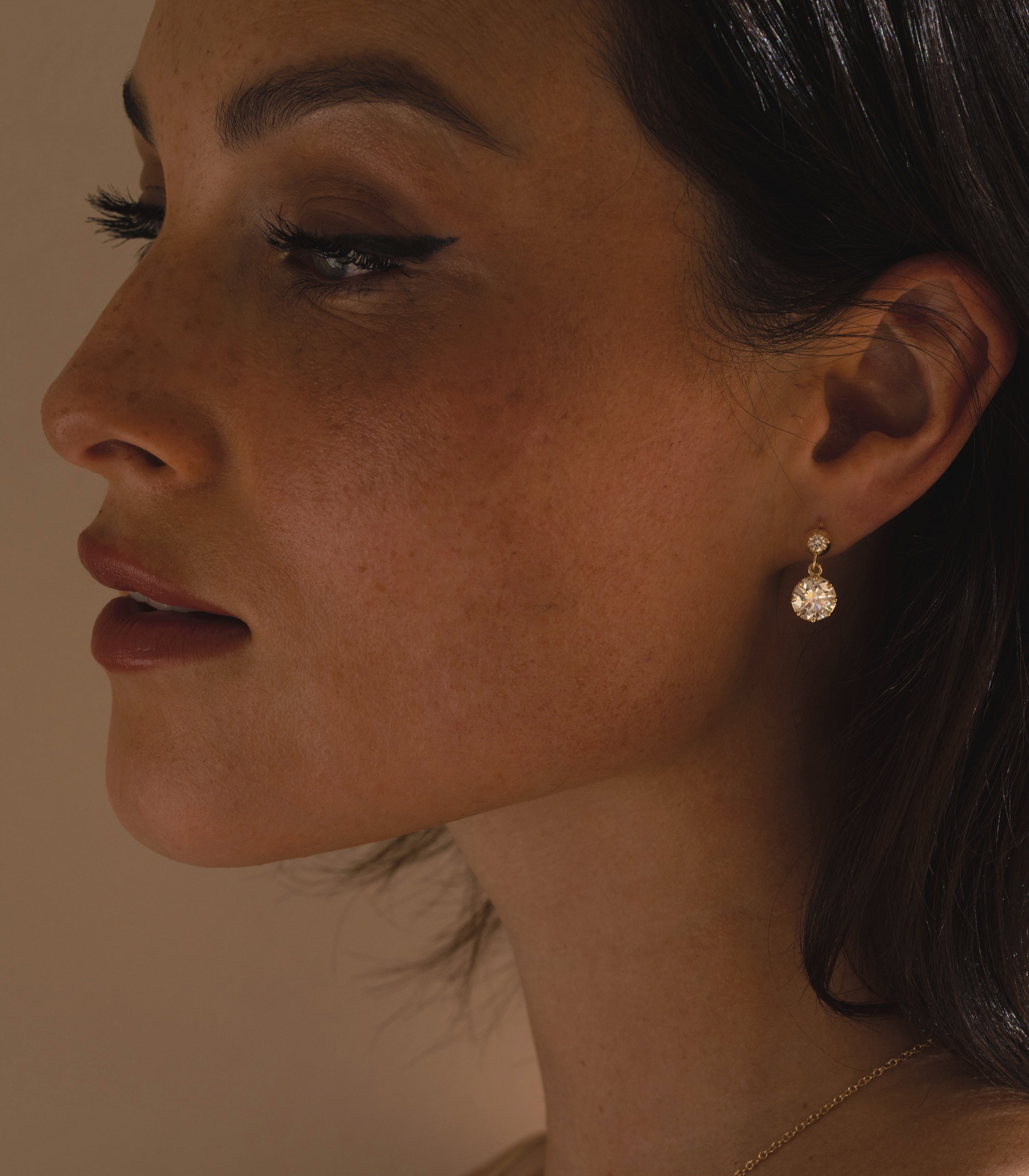 Gigi Earrings by SK-E117-ND-OEC-4.02: gold drop earrings with round sparkling stones, close-up portrait