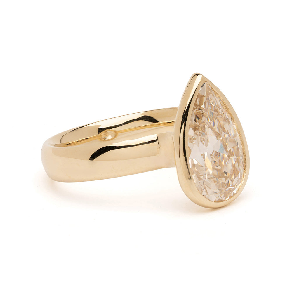 Gold ring with a pear-shaped diamond on a white background