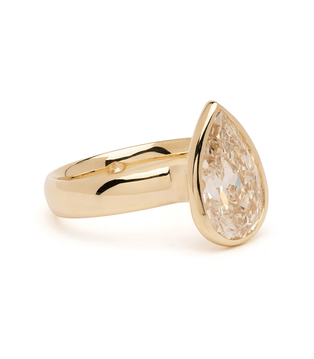 Gold ring with a pear-shaped diamond on a white background