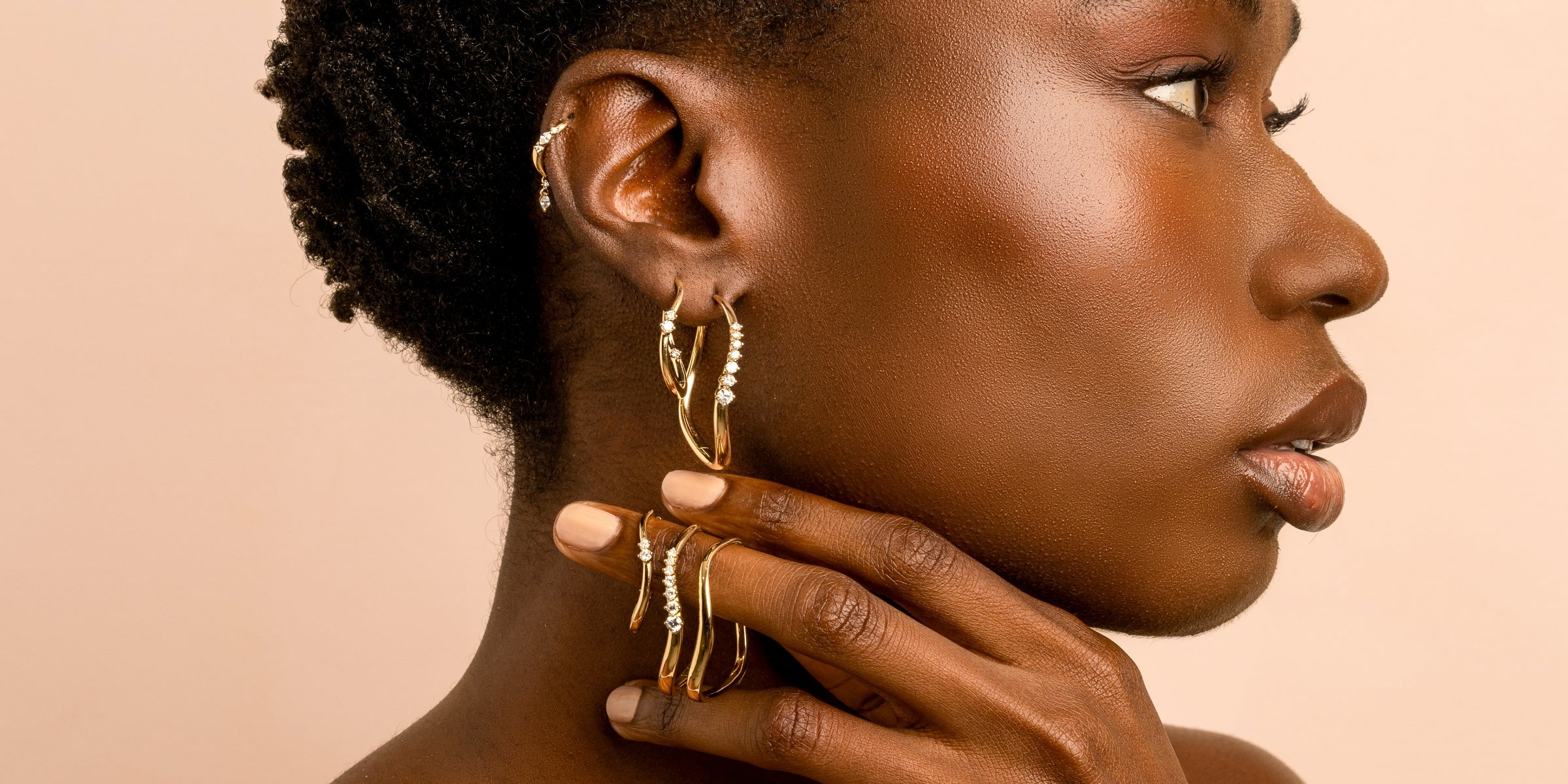 Unique engagement ring and gold hoop jewelry on a woman’s profile, with understated sparkle and hoop stones