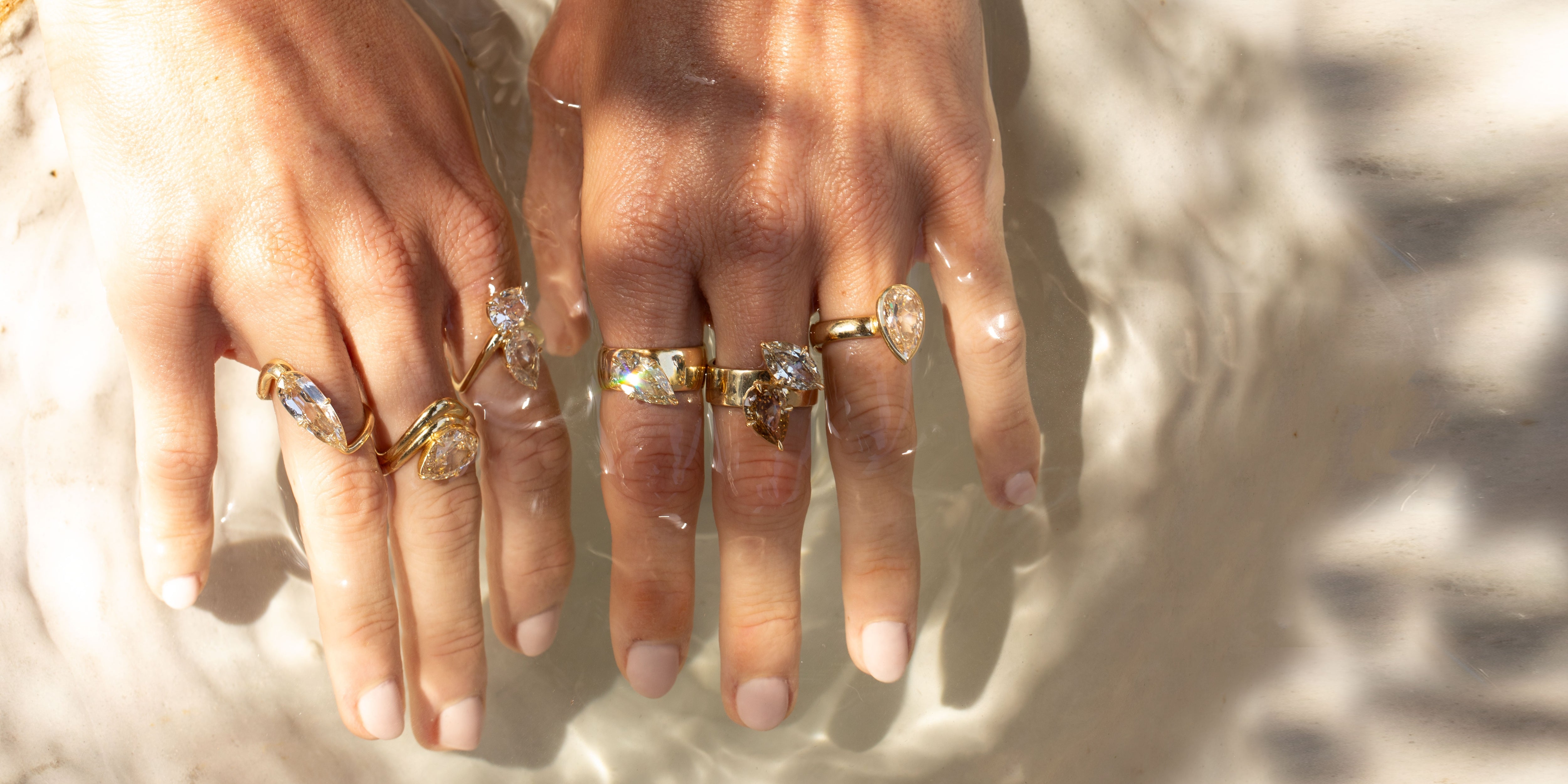 Unique engagement ring on hand with gold band and oval stones, understated and asymmetrical with multiple rings