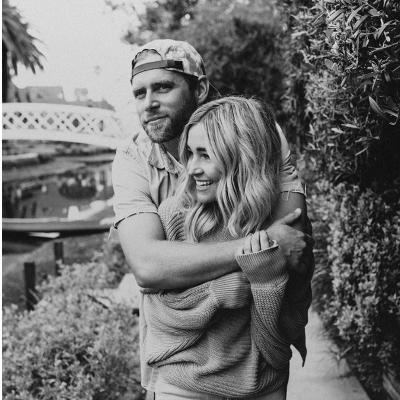 Couple embracing outdoors in a garden, arms wrapped around each other with smiling faces