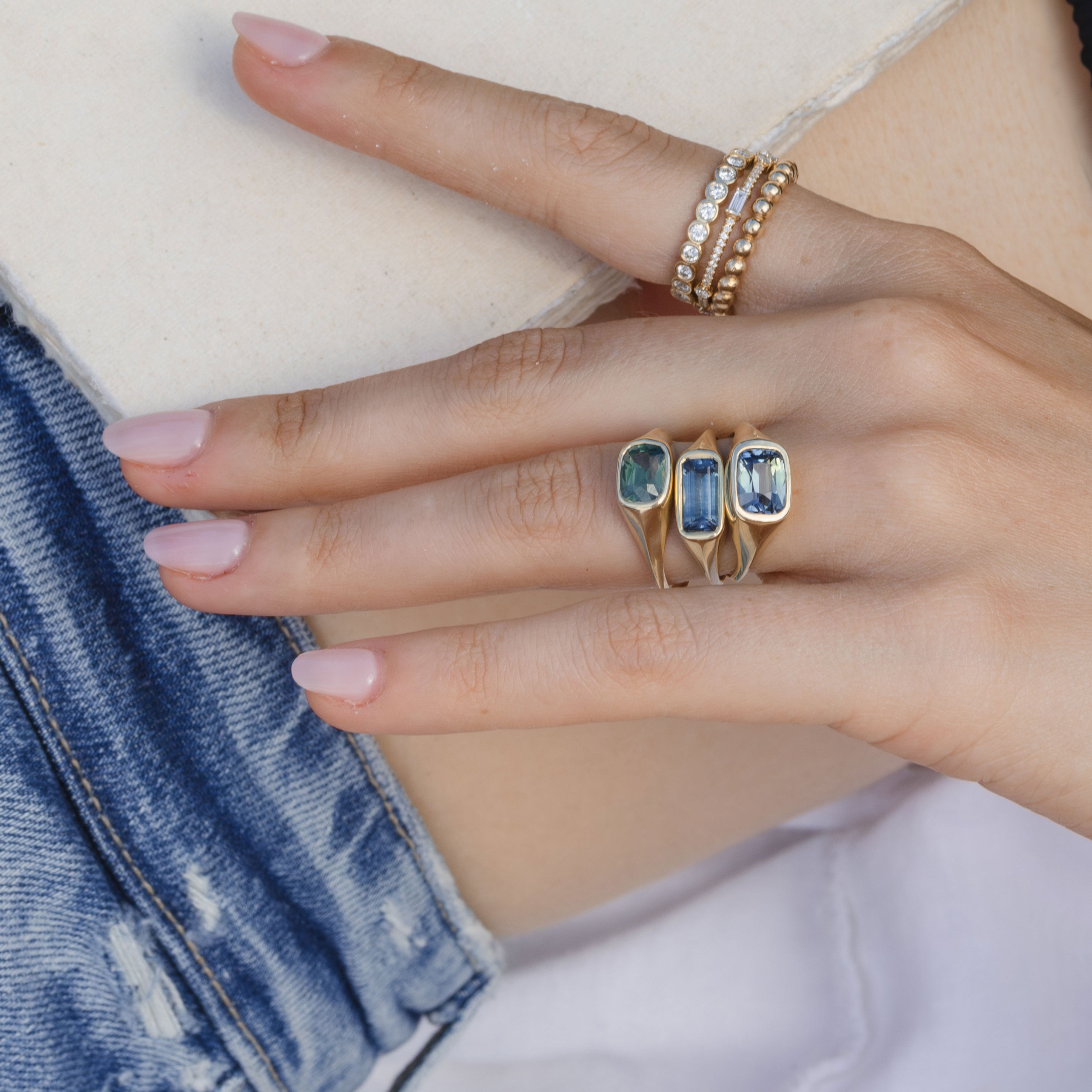 Tristan SK-R113-CC-TS-2.62 gold engagement ring with pavé stones on hand near blue denim