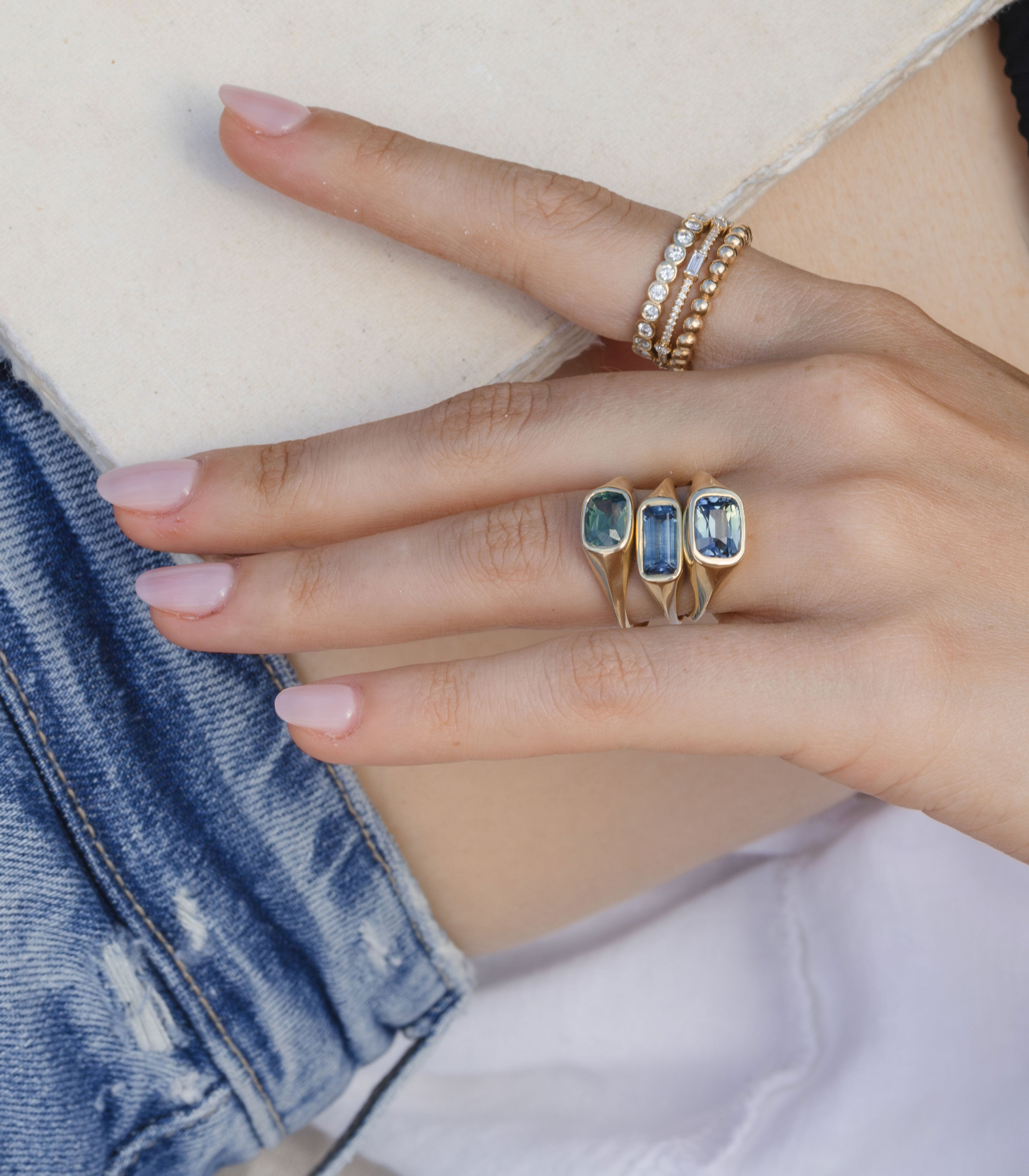 Tristan SK-R113-CC-TS-2.62 gold engagement ring with pavé stones on hand near blue denim