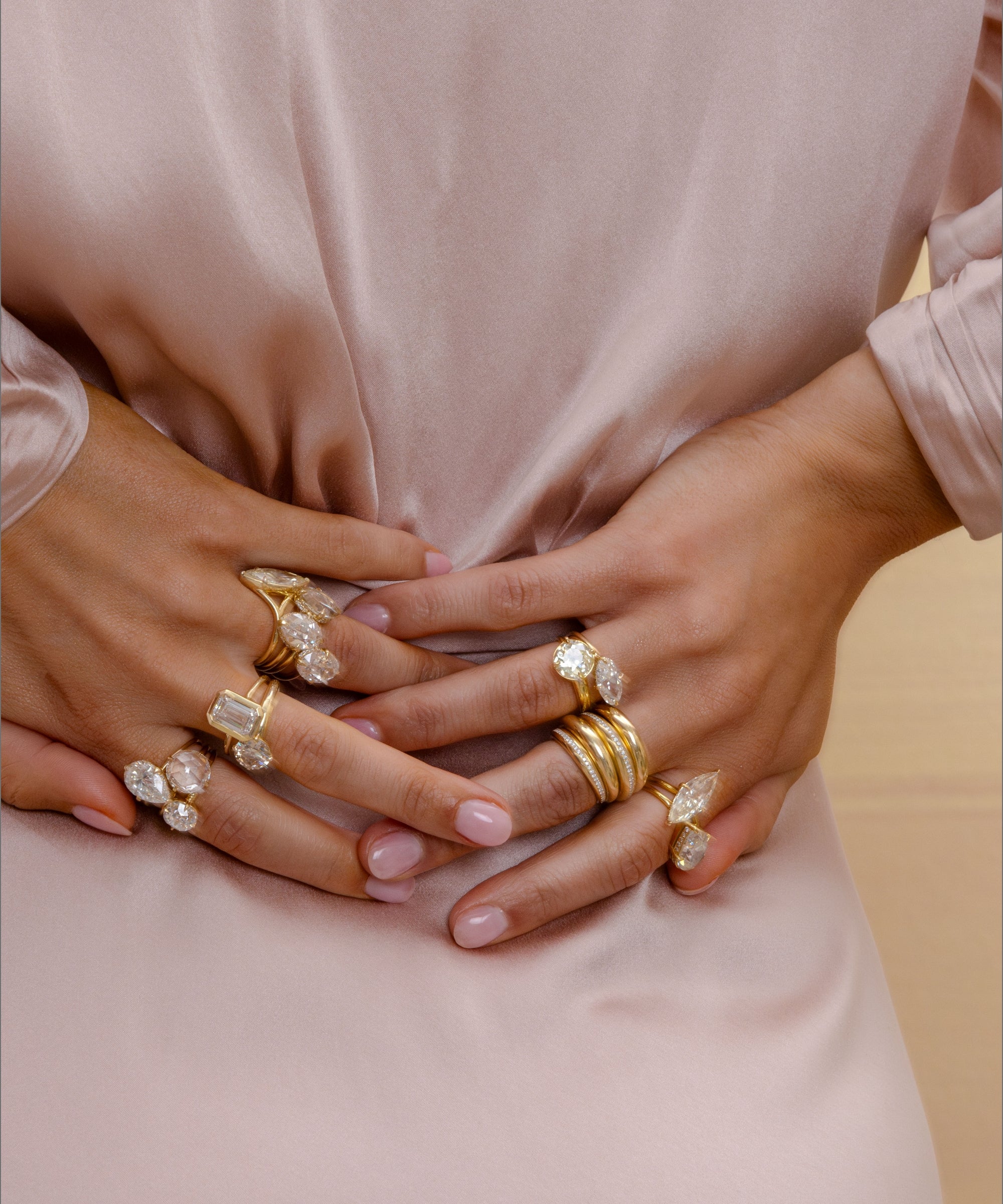 Unique engagement ring and asymmetrical engagement ring worn on clasped hands with round diamonds.