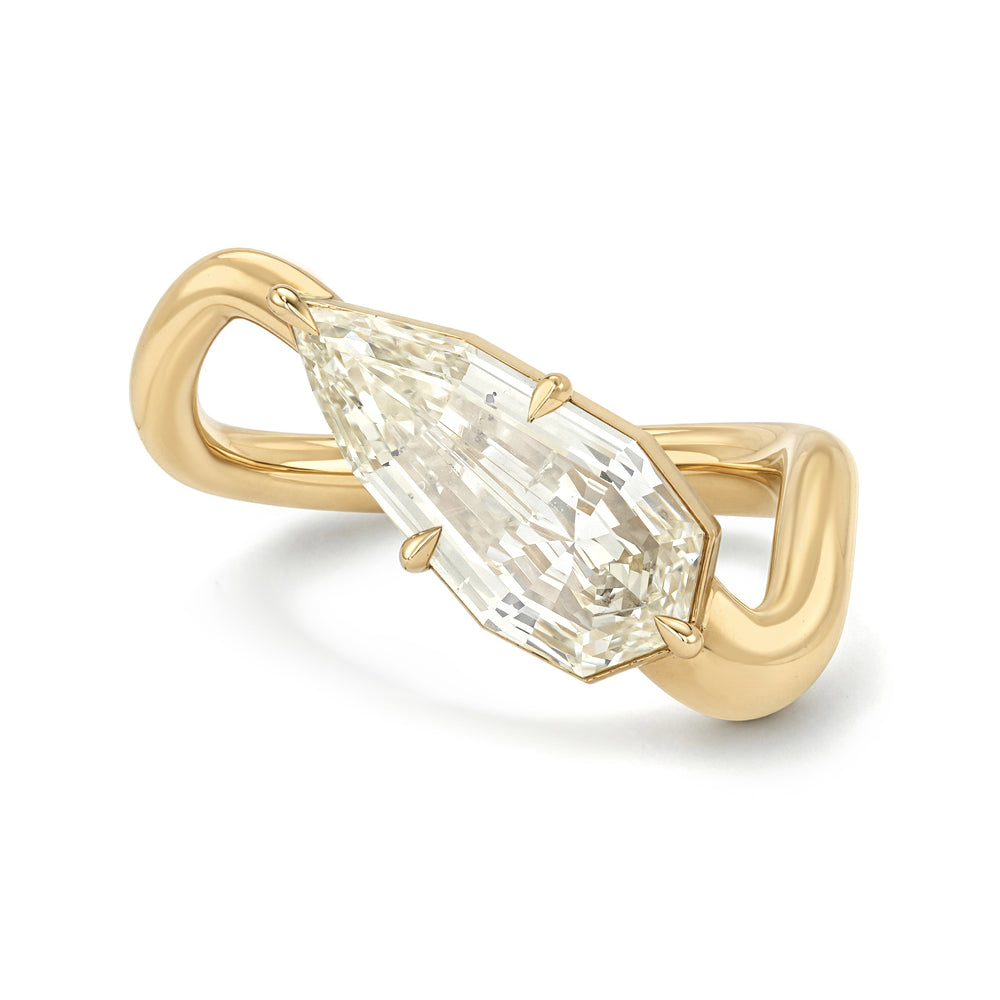 A yellow gold ring featuring a large pear step-cut diamond in a prong setting, mounted on a sculptural, twisted split-shank band, shown on a white background.