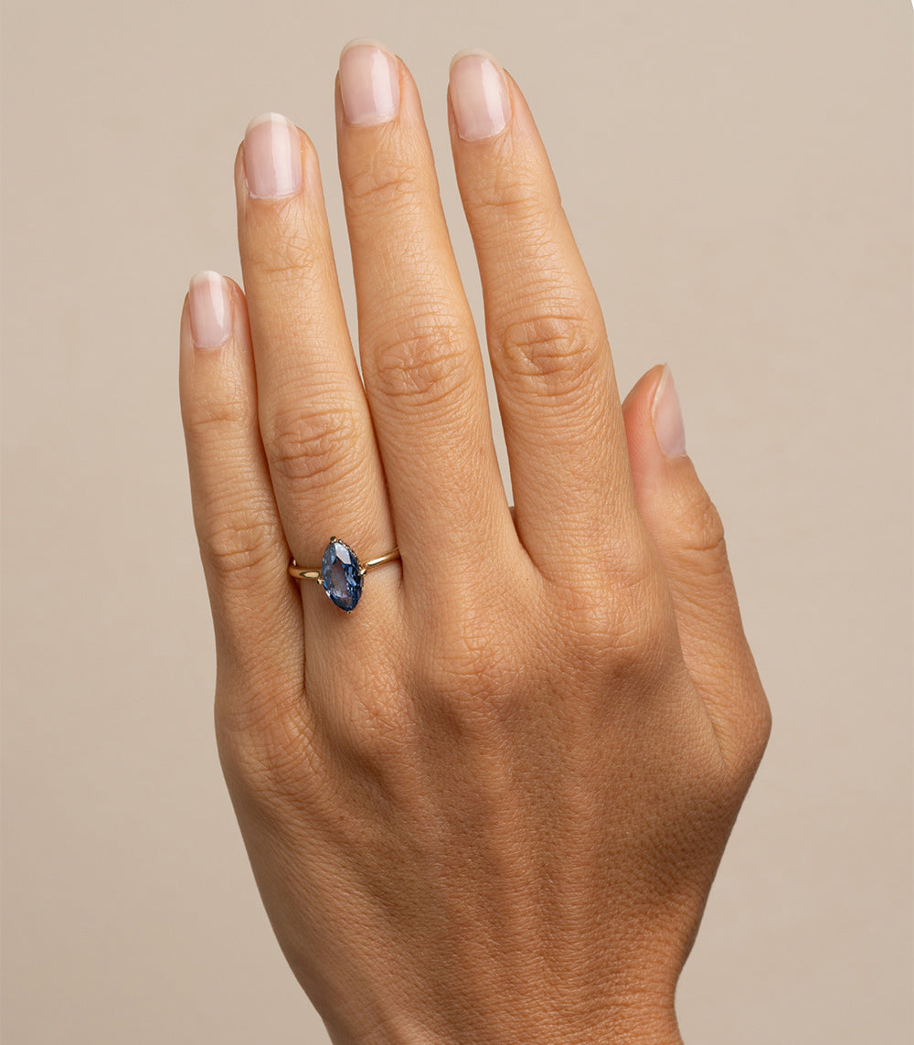 Billie SK-R94-BS-NS-MQ-2.38 understated gold ring with blue oval stone setting on fingers