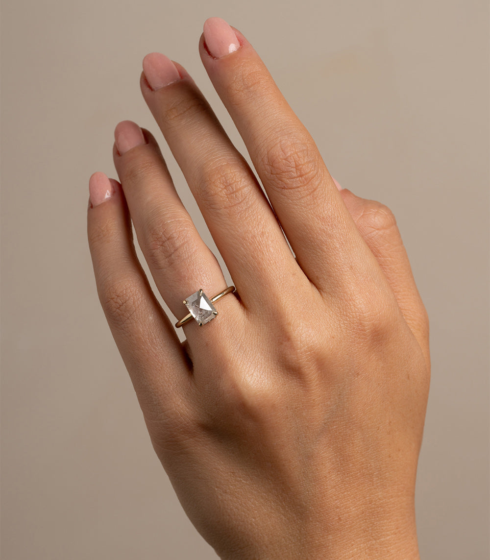 Billie SK-R94-NS-SP-RecRC-2.36 unique engagement ring on a hand, gold band with a square-cut clear stone