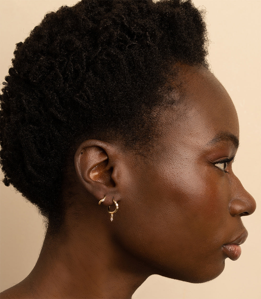 Small Melt Hoops ML-E4 earrings in shiny gold with matte texture and a dangling charm—side profile view