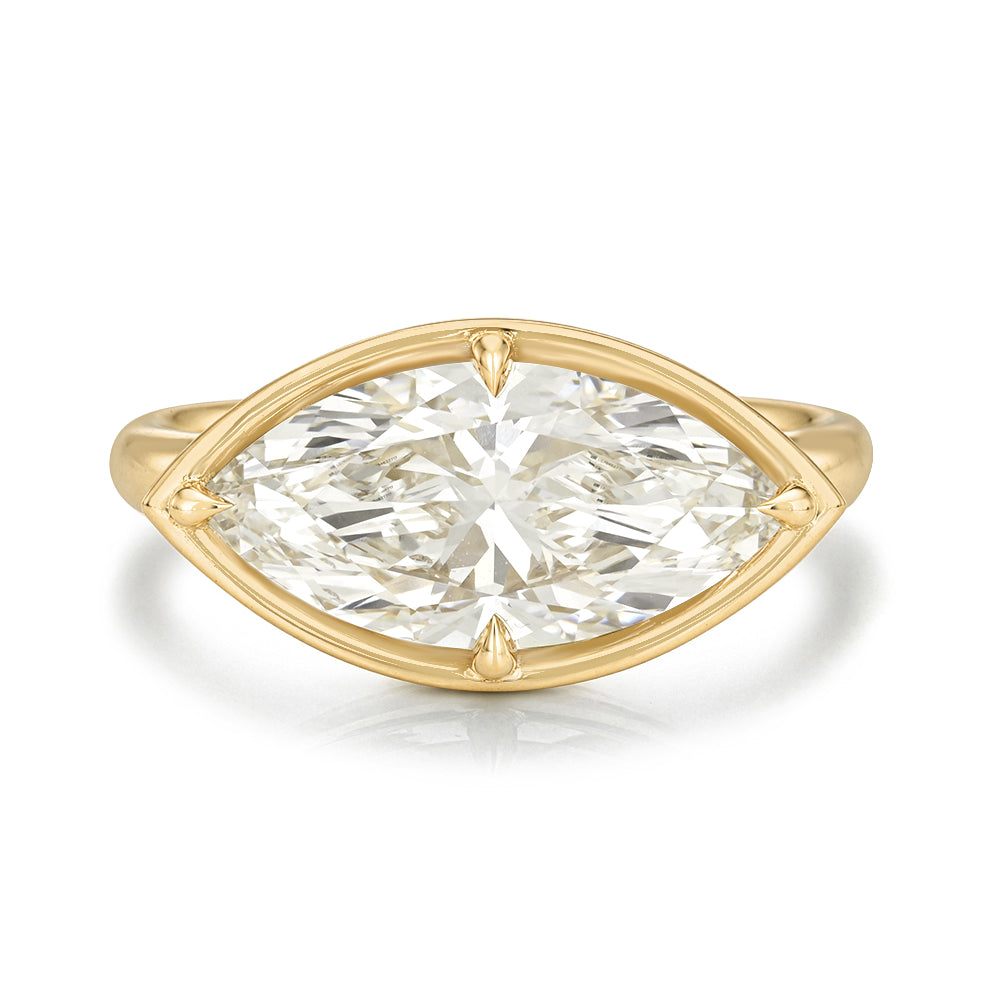 A yellow gold ring featuring a large marquise brilliant-cut diamond in a prong setting, shown on a clean white background with a soft reflection.