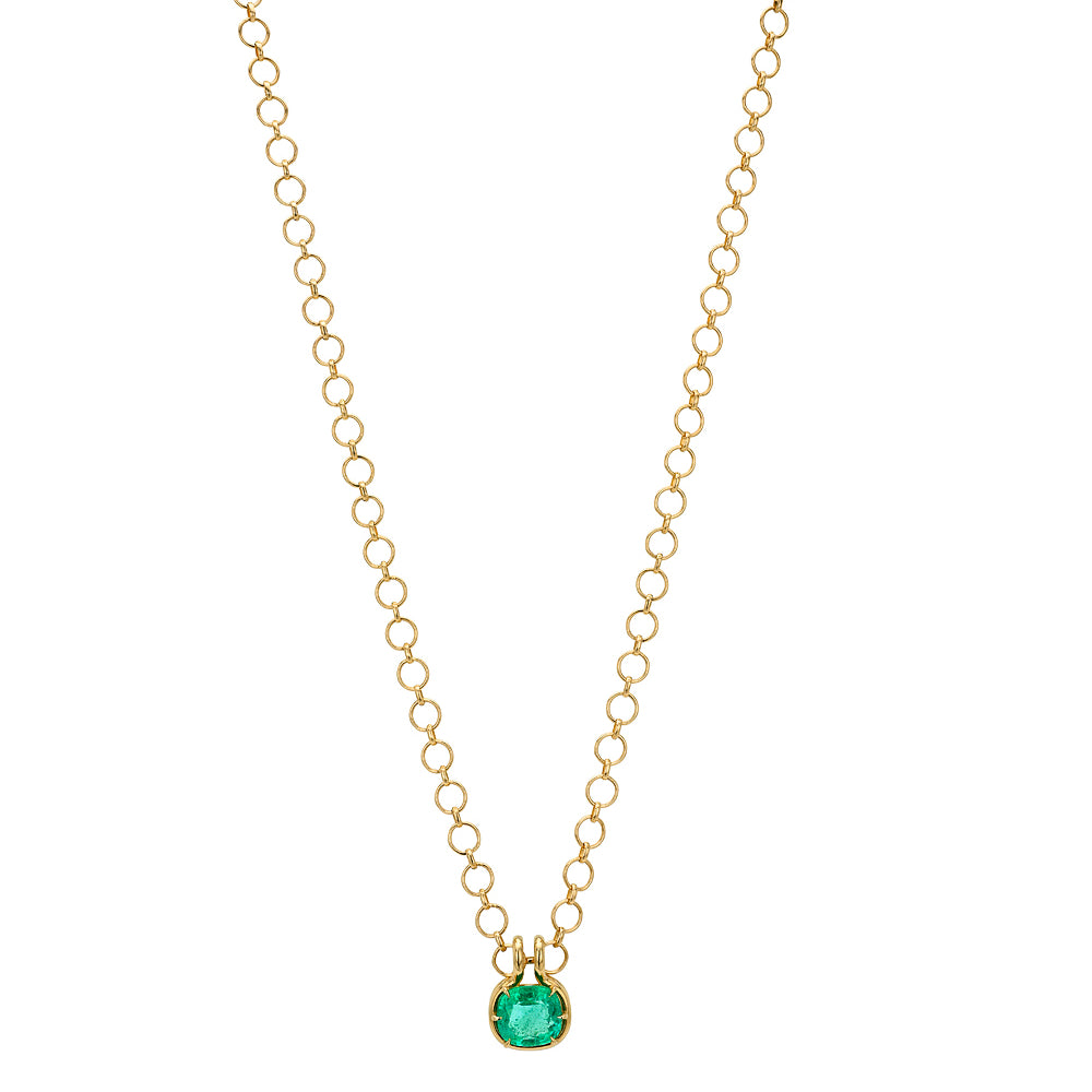 A delicate gold loop chain necklace with a small, elongated cushion green emerald pendant, displayed against a solid white background.