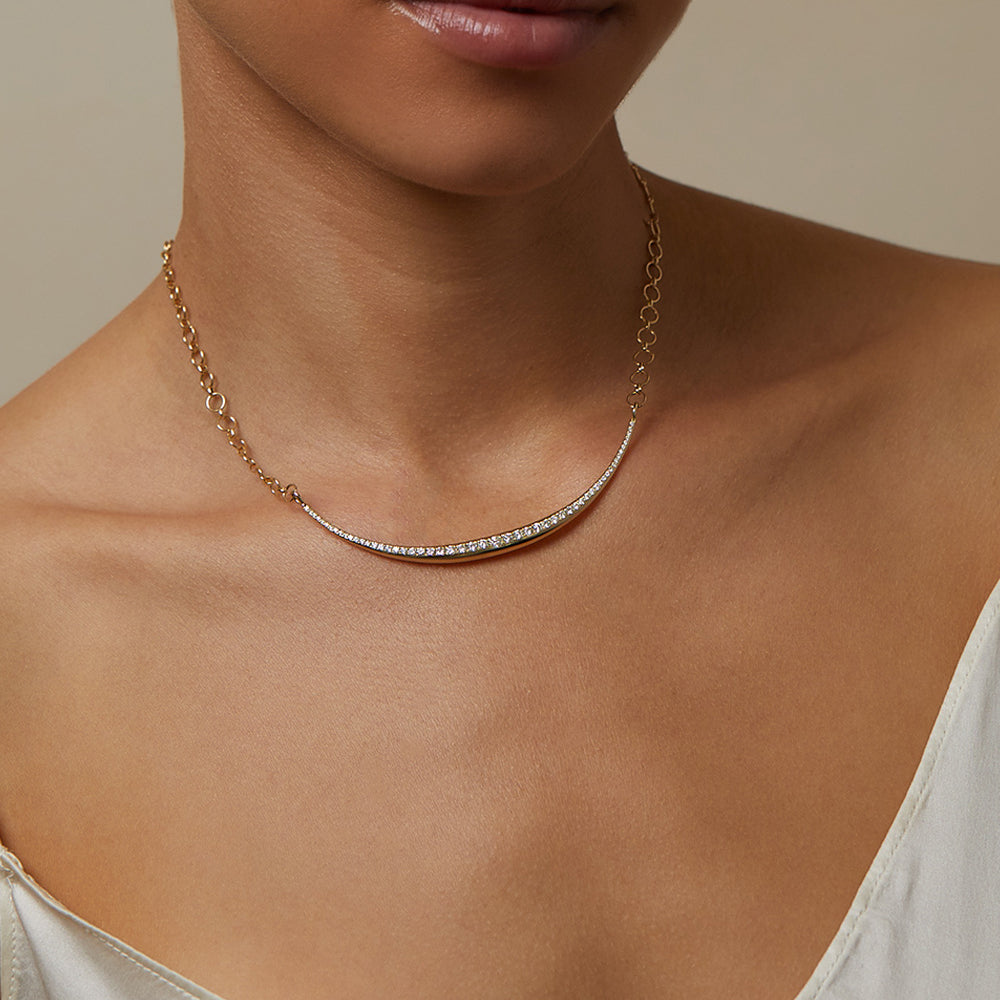 The Luna SK-N4 gold necklace with a curved diamond-studded bar, close-up on collarbone.