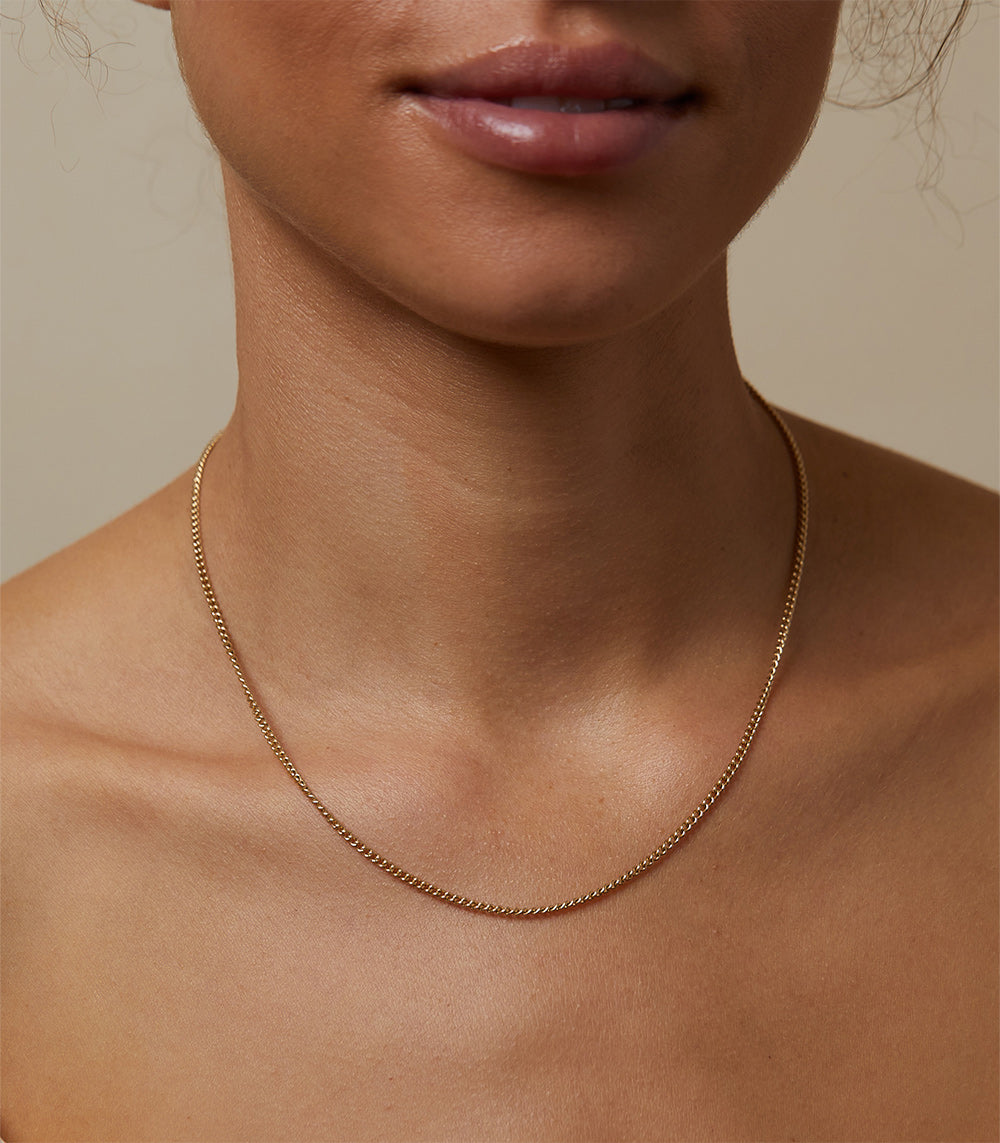 The Sexy CN-C10 necklace in fine gold chain with delicate curve on a model’s neckline.