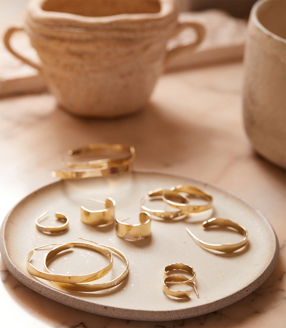 Mini Torn Paper Ear Cuff by P-EC1 in 14K yellow gold, shiny hinged ear cuff on beige tray