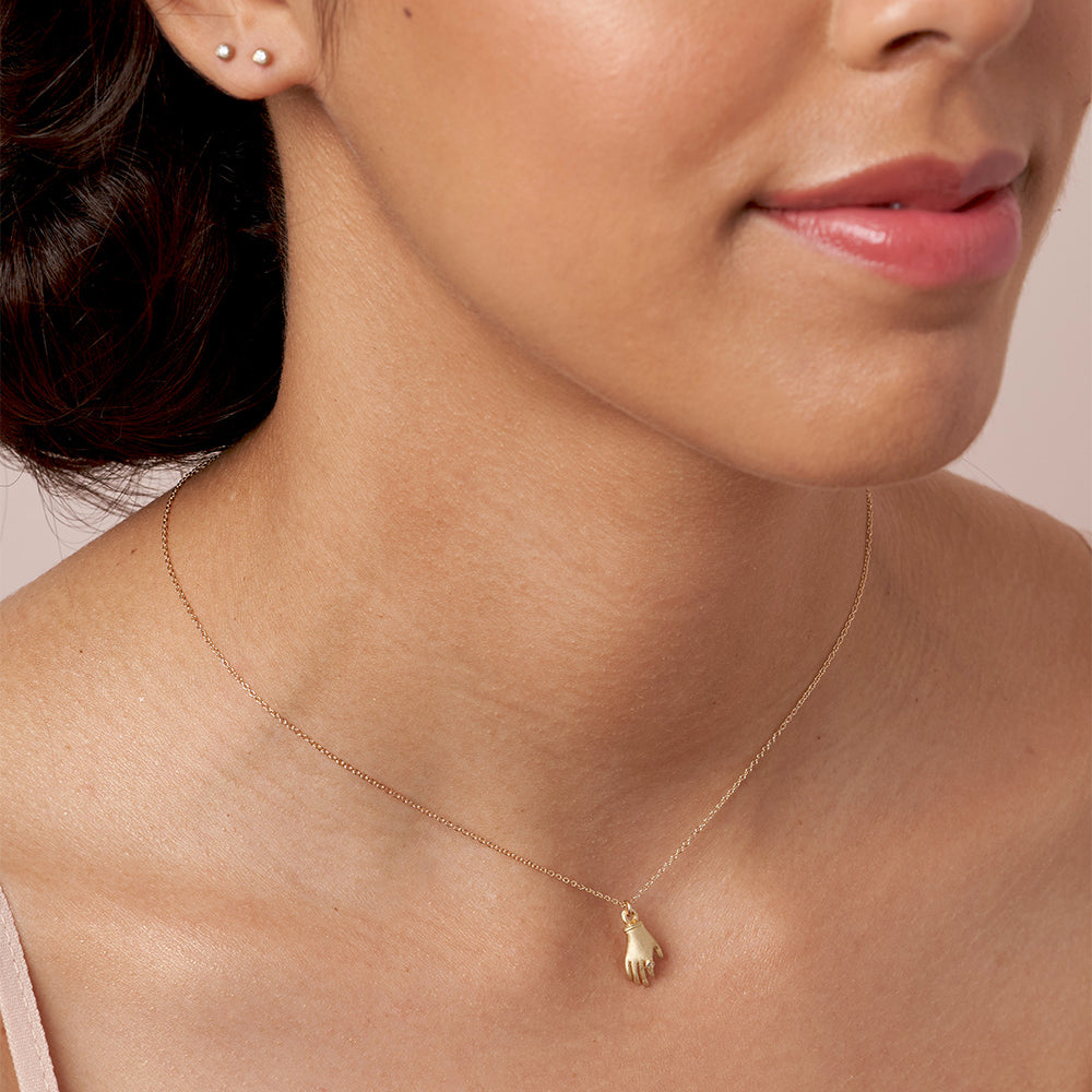 Hand It to You SK-P7 shiny 14K yellow gold necklace with hand charm, paired with small stud earrings