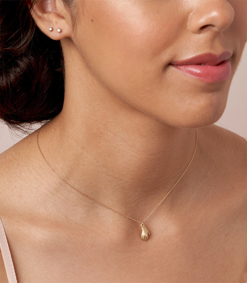 Hand It to You SK-P7 shiny 14K yellow gold necklace with hand charm, paired with small stud earrings