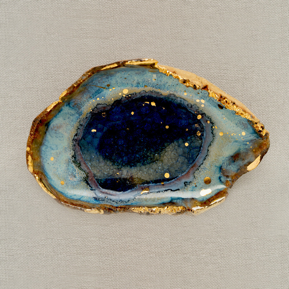 Azure Ring Dish by G-007, blue geode-style ring dish with gold-speckled edge on beige fabric.