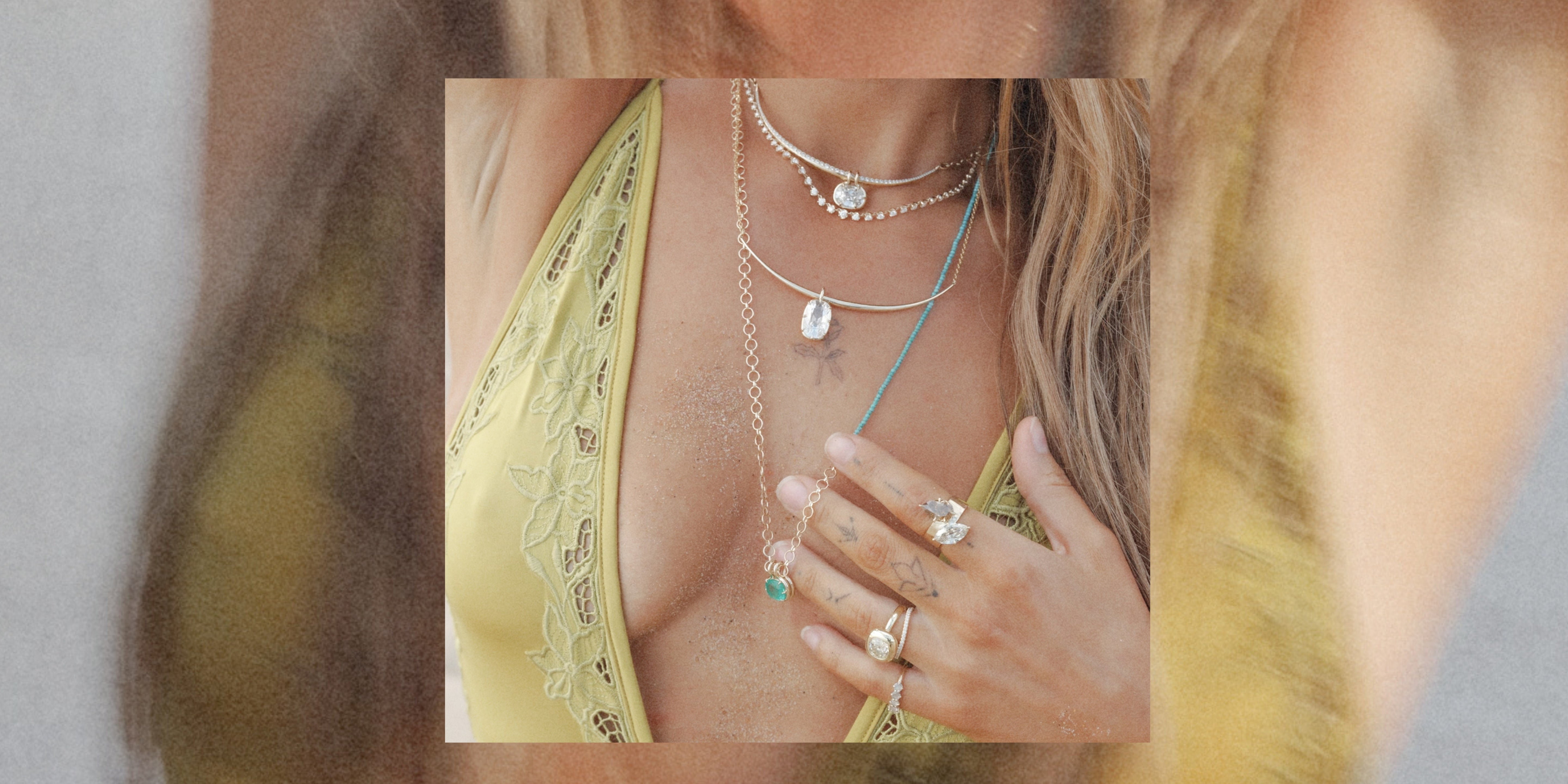 A close-up lifestyle shot of a woman wearing layered silver necklaces and rings, including a turquoise pendant necklace and a star charm, styled with a yellow lace halter top.