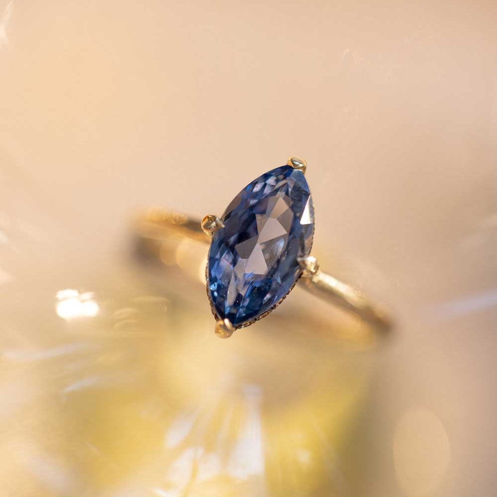 Billie SK-R94-BS-NS-MQ-2.38 engagement ring in yellow gold with oval blue gemstone, soft glow