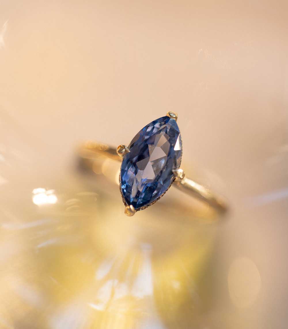 Billie SK-R94-BS-NS-MQ-2.38 engagement ring in yellow gold with oval blue gemstone, soft glow