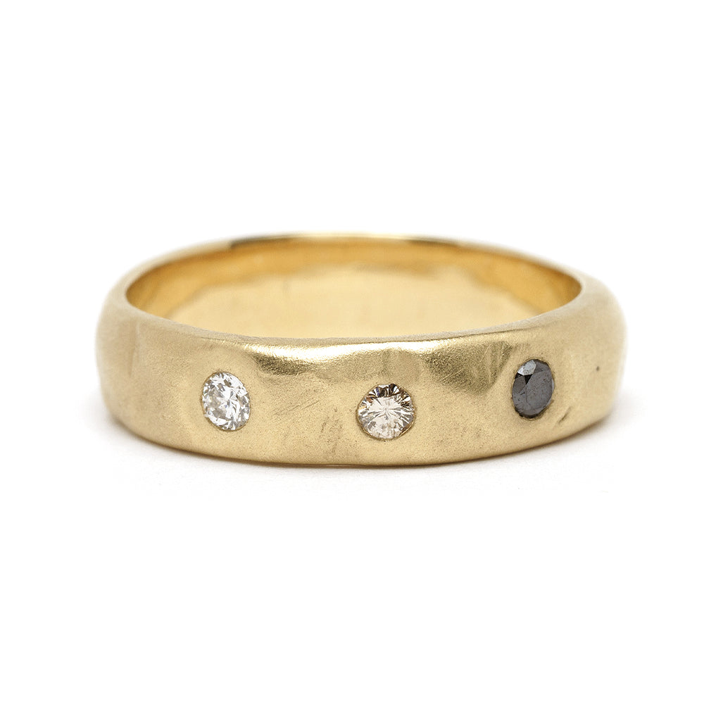 Dusk till Dawn GN-R3 gold 3 stone engagement ring with two round diamonds and one dark stone, shiny.