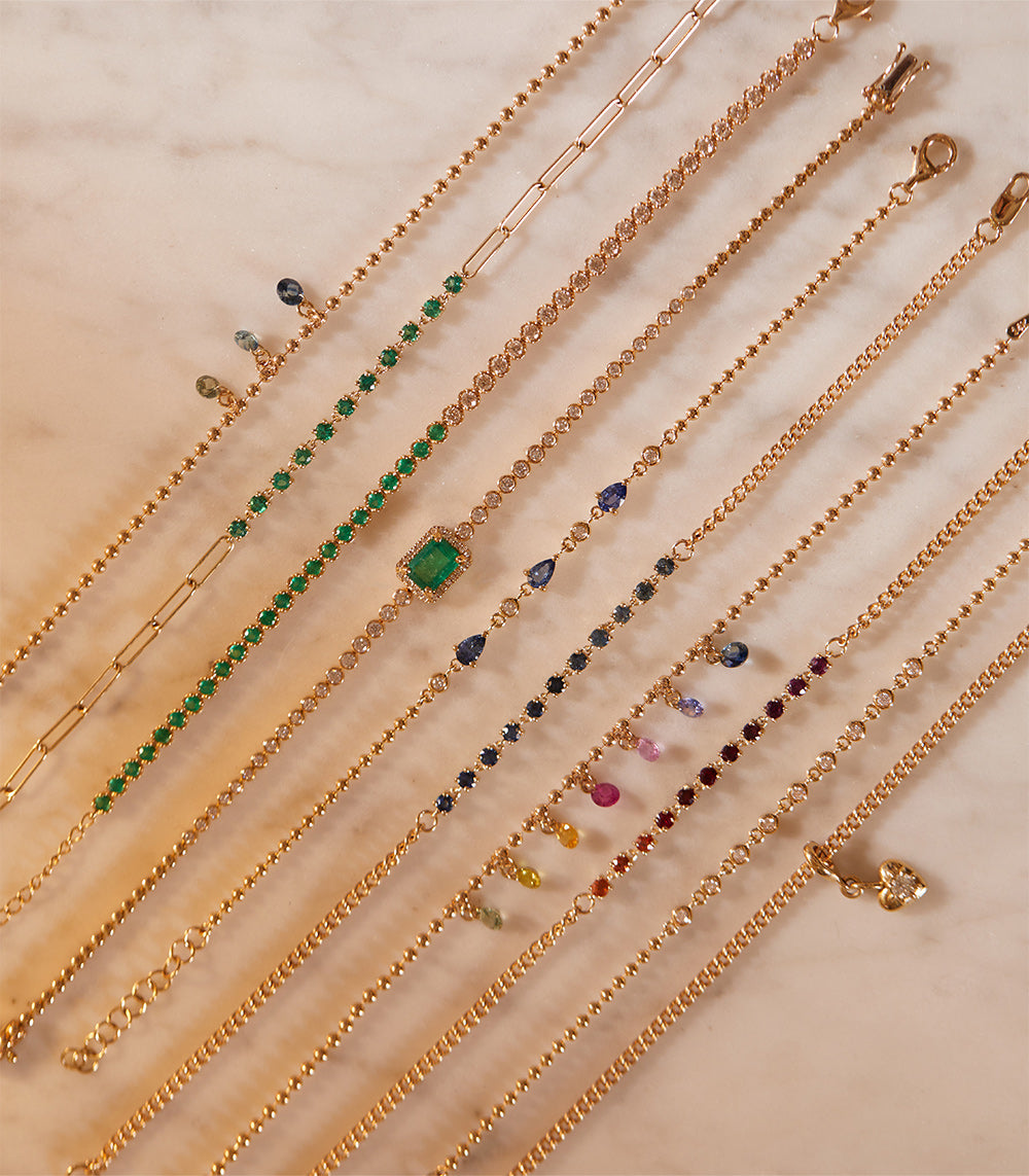 The Sunset SK-B6 gold gemstone necklaces with green, blue, and pink stones on a light beige background