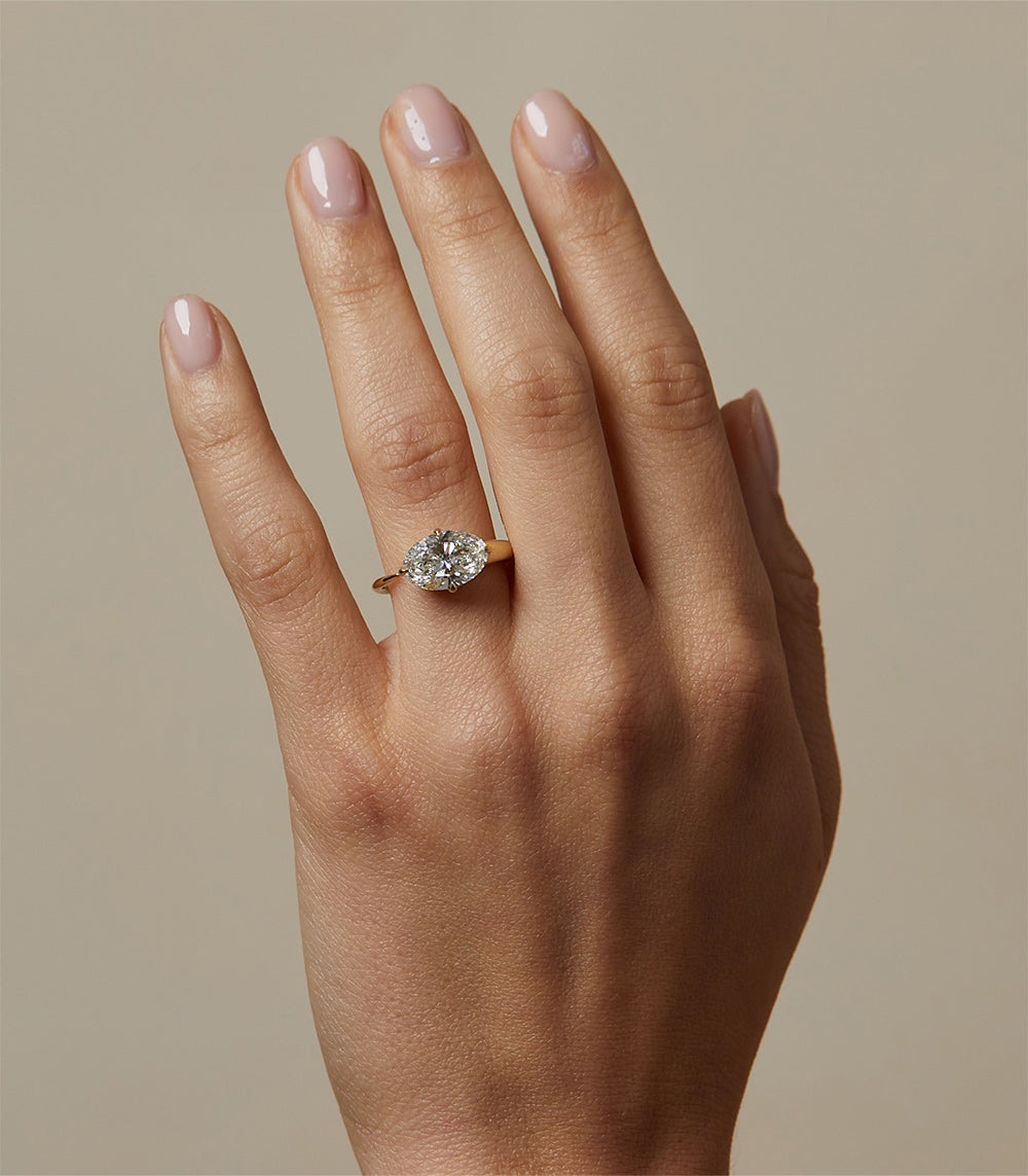 Sloane SK-R86-EW-LGD-OB-2.67 gold engagement ring with round-cut diamond solitaire on hand, soft light