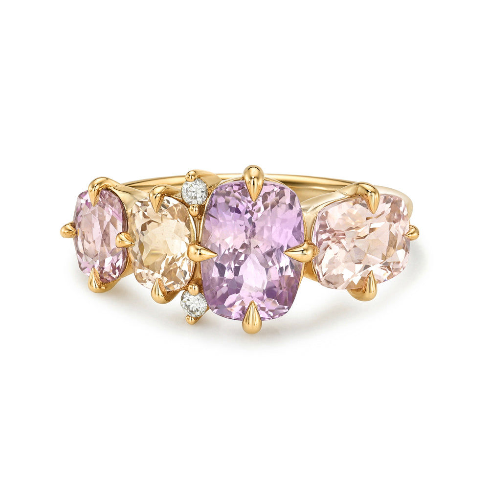 A gold three-stone ring featuring a large oval light purple amethyst sapphire, flanked by smaller peach and pale yellow citrine sapphires, with tiny clear accent diamonds, set against a plain white background.