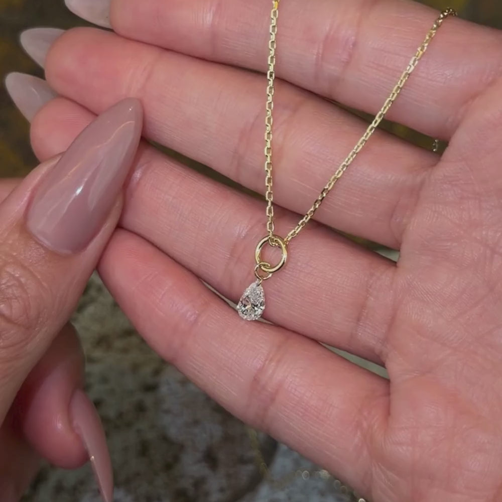 14K yellow gold chain necklace with a pear brilliant cut diamond pendant shown with hands.