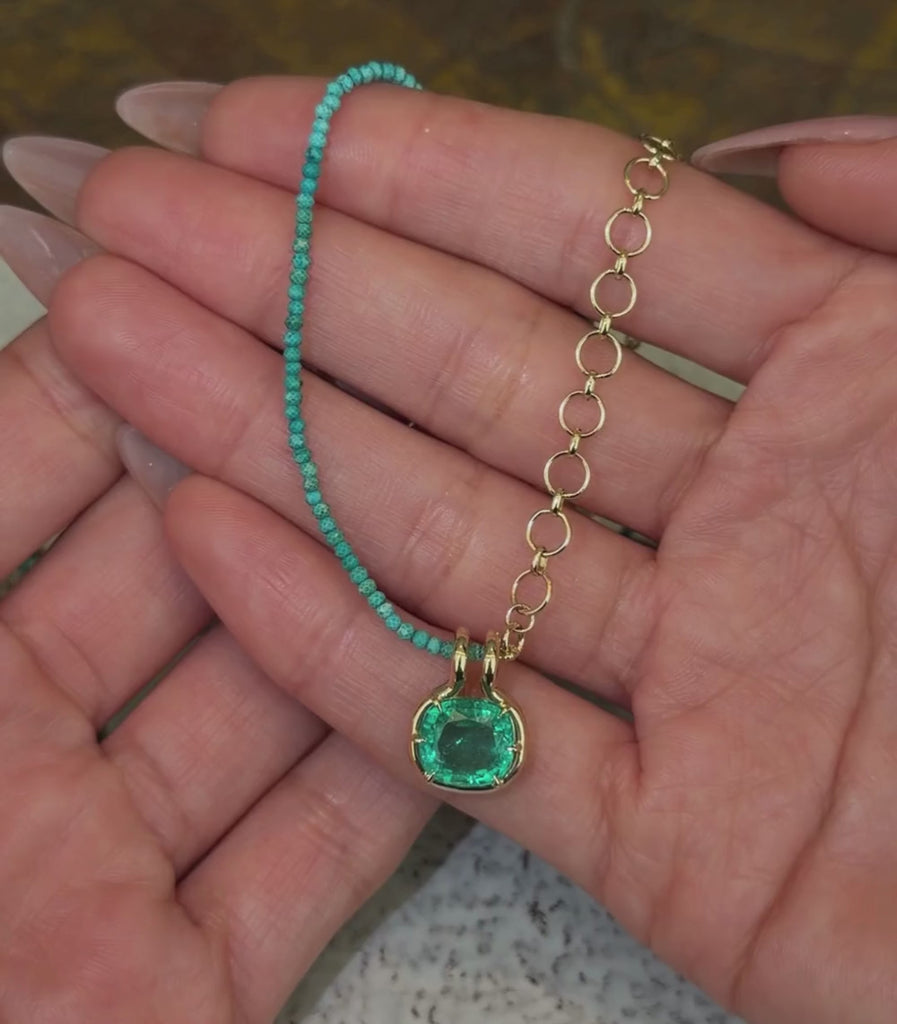 14K yellow gold loop chain and turquoise beaded necklace with an elongated cushion emerald pendant shown with hands.