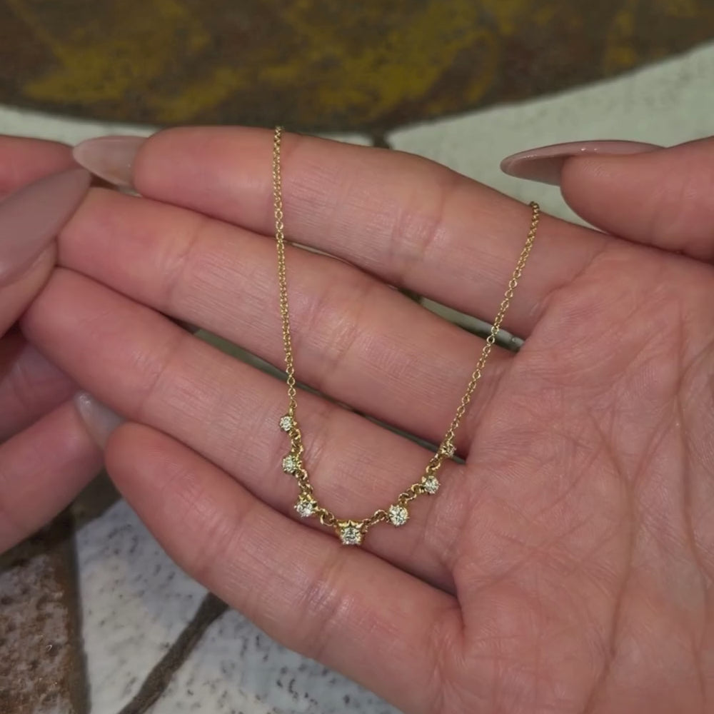 14k yellow gold chain necklace with 7 diamond collet details shown with hands.
