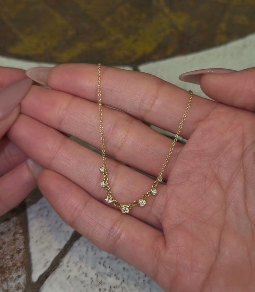 14k yellow gold chain necklace with 7 diamond collet details shown with hands.