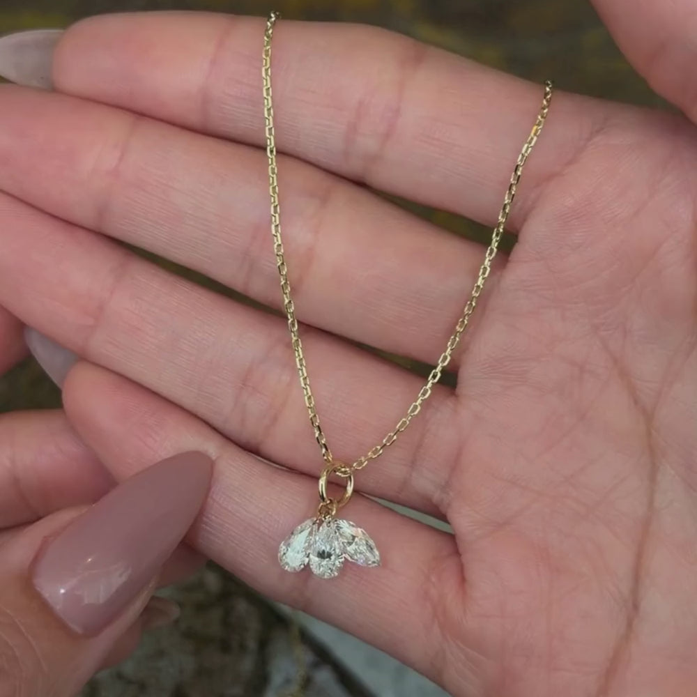 14K yellow gold chain necklace with two pear brilliant cut diamond pendants and one marquise brilliant cut diamond pendant shown with hands.