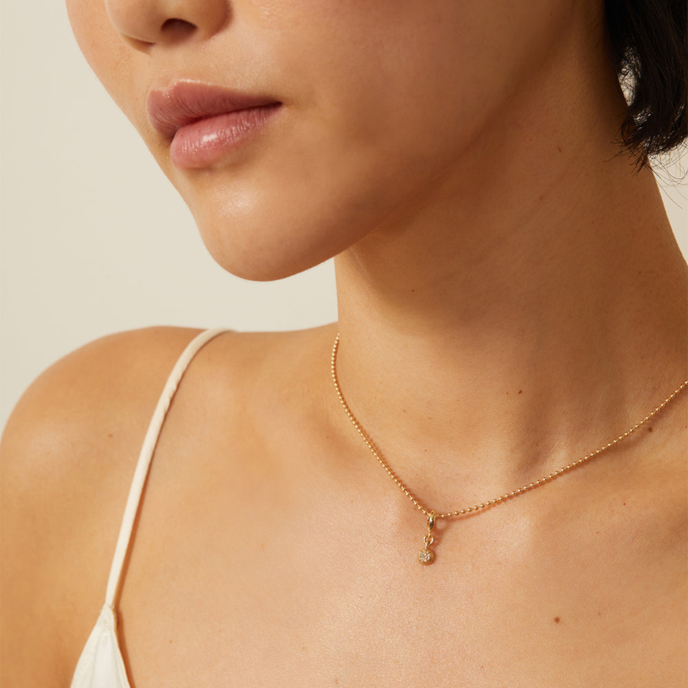 Cora Mini Charm KM-P11 charm necklace in gold with a shiny mini pendant charm at the collarbone