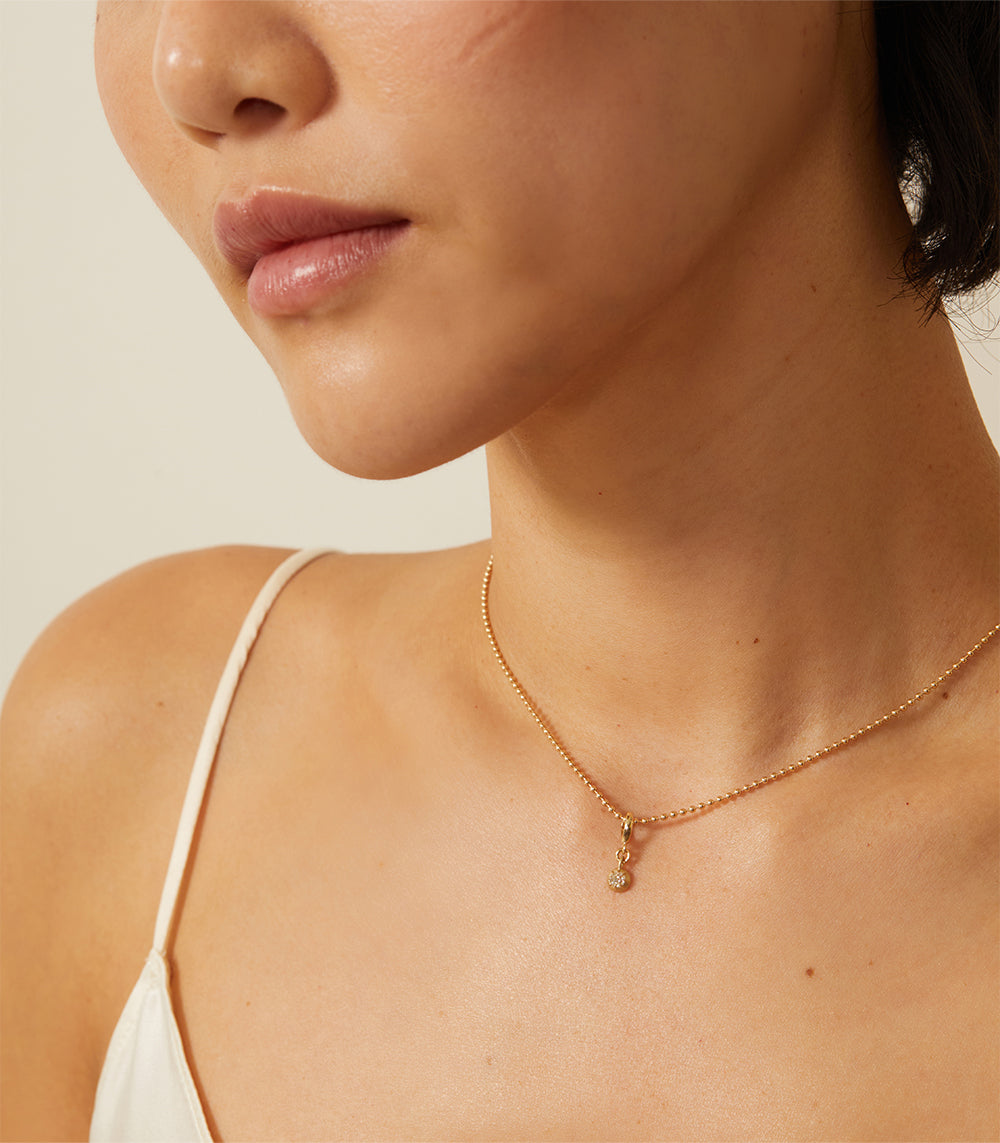 Cora Mini Charm KM-P11 charm necklace in gold with a shiny mini pendant charm at the collarbone