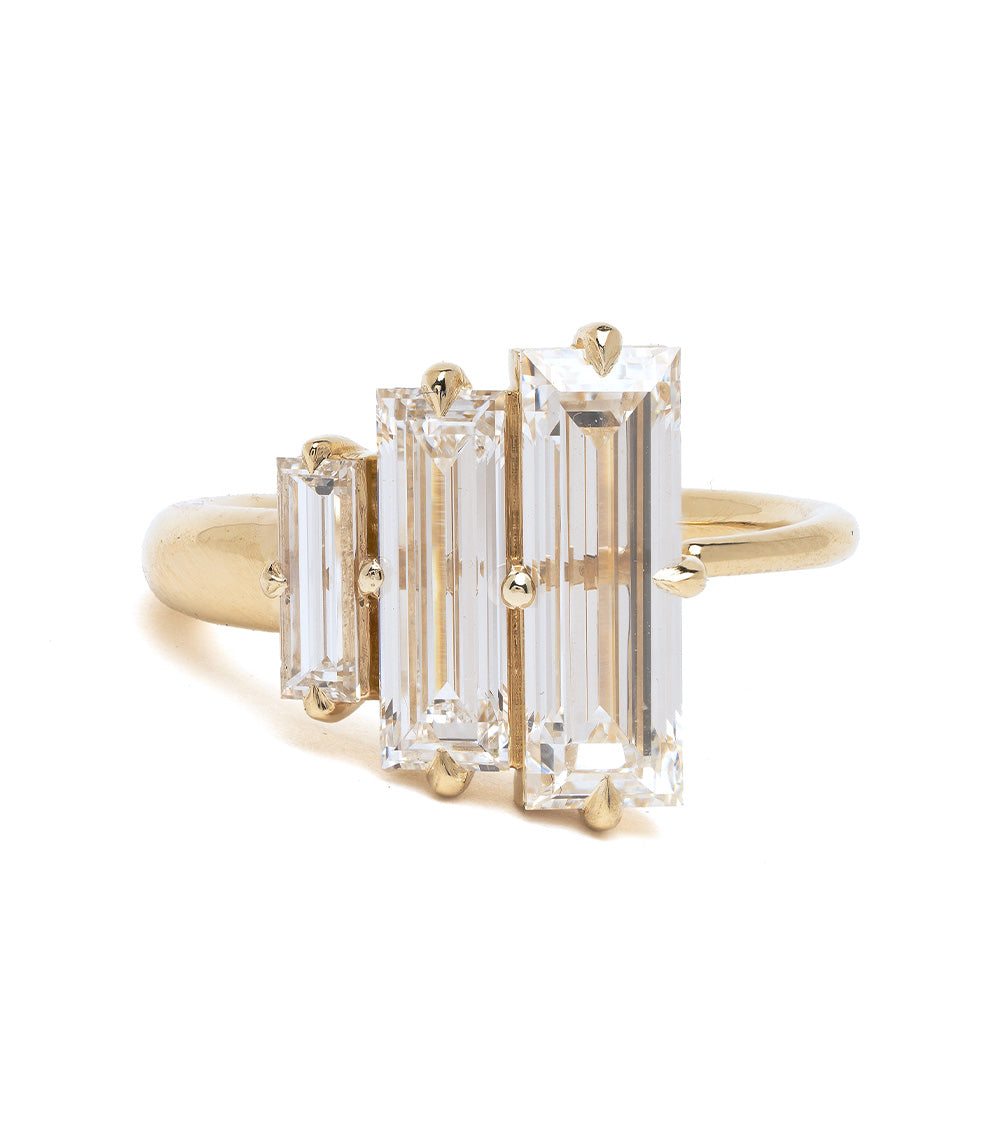 Gold ring with three emerald-cut diamonds on a white background