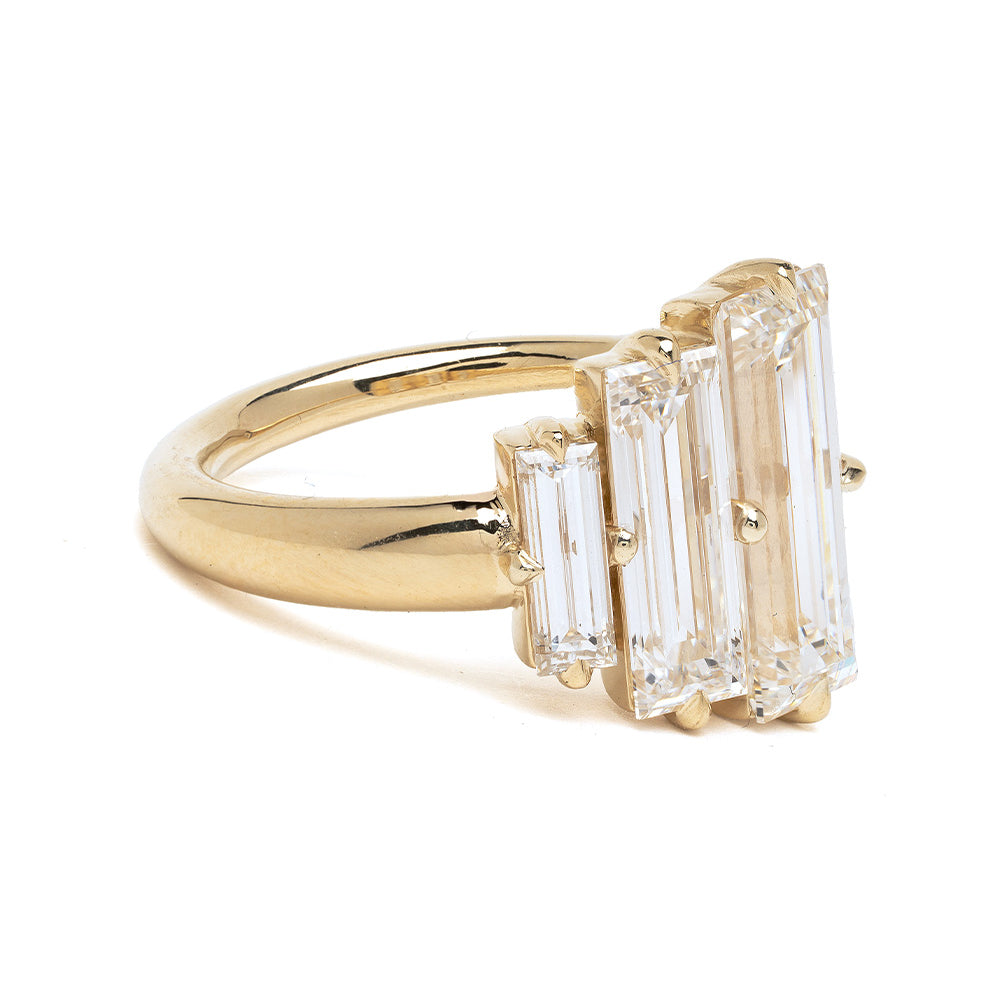 Gold ring with three rectangular diamonds on a white background