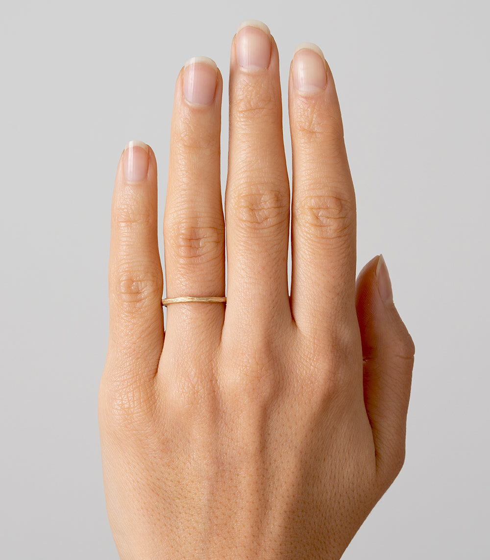 Twig Band ES-R1 ring in 14K yellow gold with shiny slim band on hand, natural skin texture