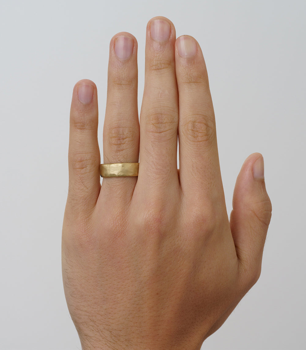 Raw Texture Wedding Band by M-R1-7 in 14K yellow gold, raw hammered matte finish on hand.