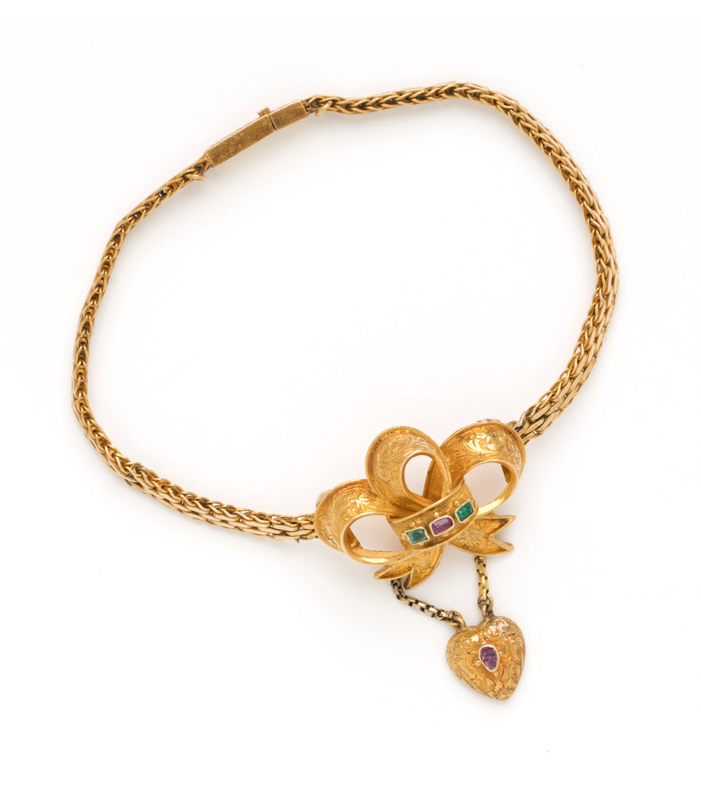 Spellbound Bow Bracelet VC-B11 gold chain bracelet with bow-and-heart charm and green and purple stones.