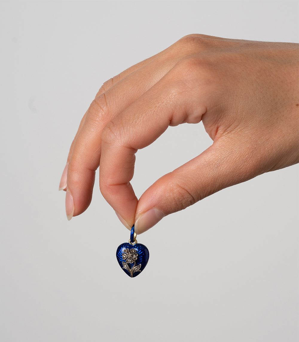 True Blue VC-N68 heart pendant in deep blue with small silver-toned gemstone floral detail held by hand